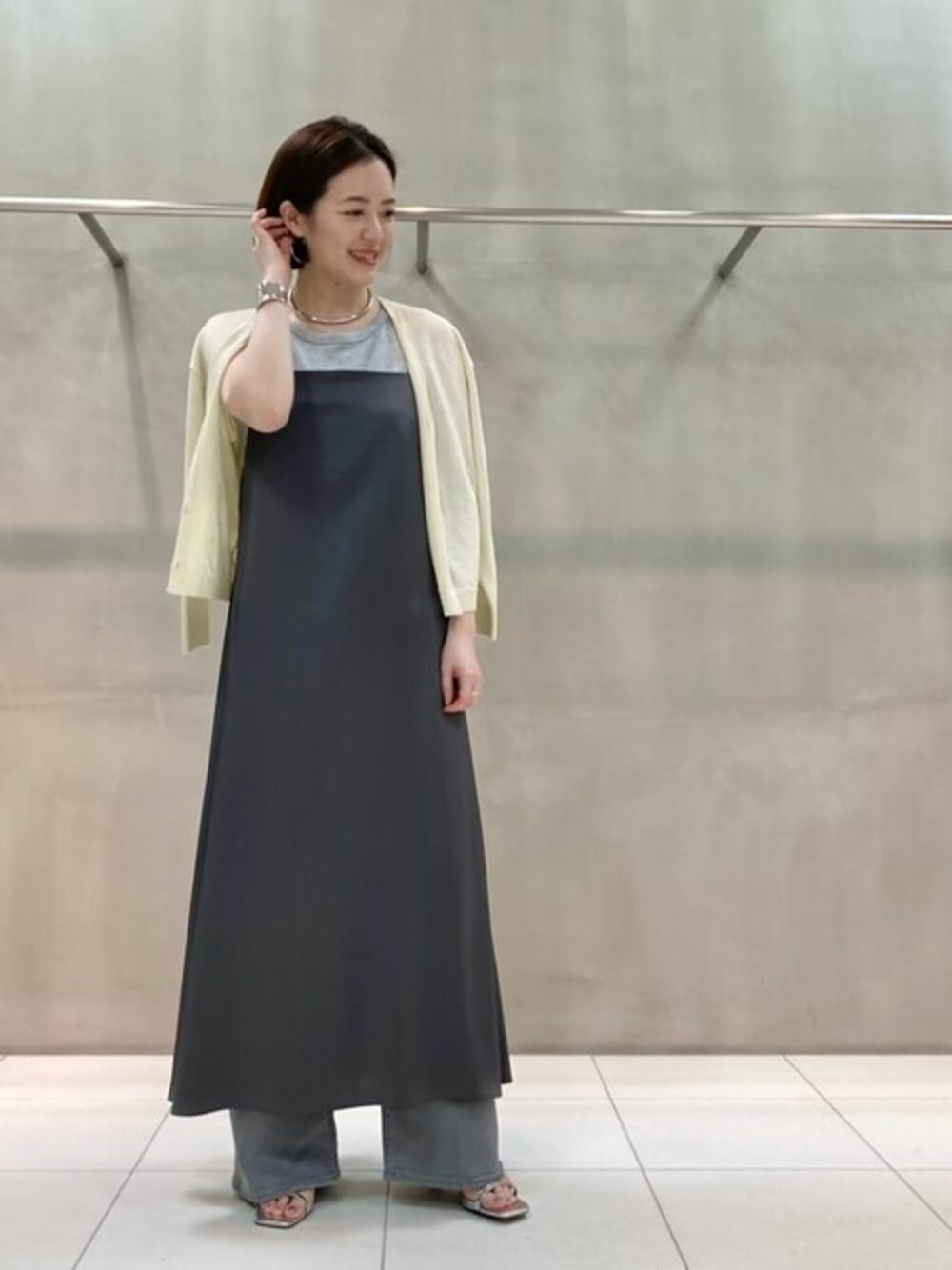 イエロー系のカーディガン/ボレロ、グレー系のワンピース、グレー系のデニムパンツを着用したレディースの春コーディネートの1枚目の写真