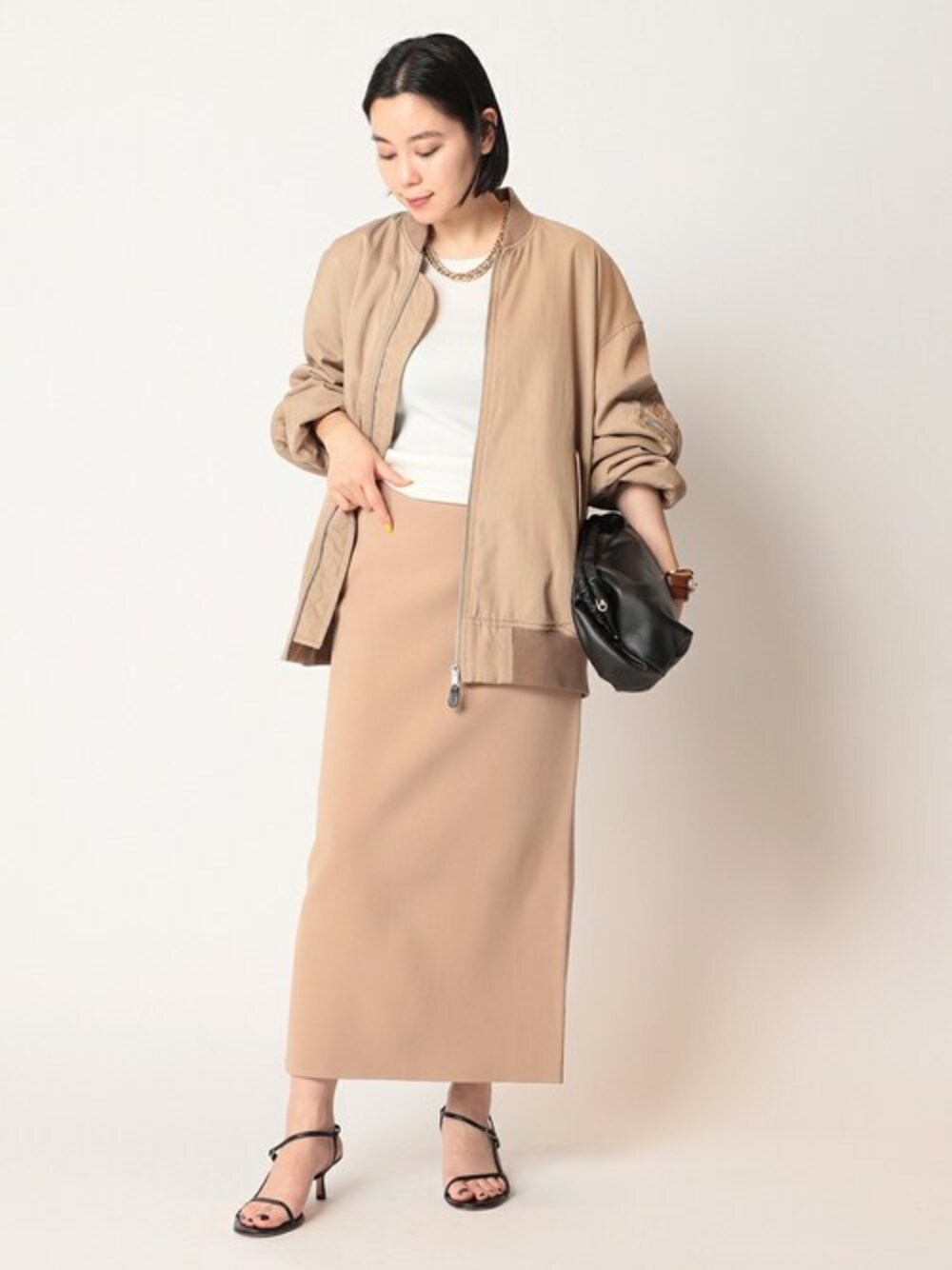 ホワイト系のタンクトップ、ベージュ系のスカートを着用したレディースの春コーディネートの1枚目の写真