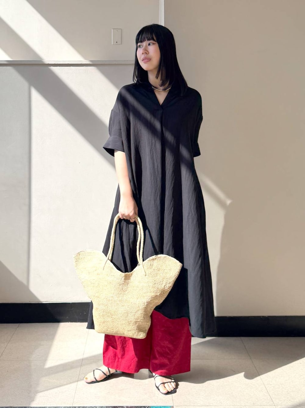 レッド系のその他パンツ、ブラック系のワンピース、ベージュ系のかごバッグを着用したレディースの春コーディネートの1枚目の写真