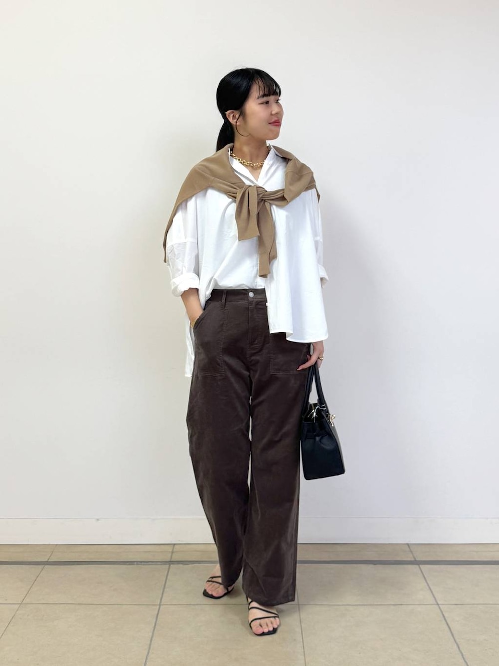 ブラック系のショルダーバッグ、ホワイト系のシャツ/ブラウス、ベージュ系のニット/セーターを着用したレディースの夏コーディネートの1枚目の写真