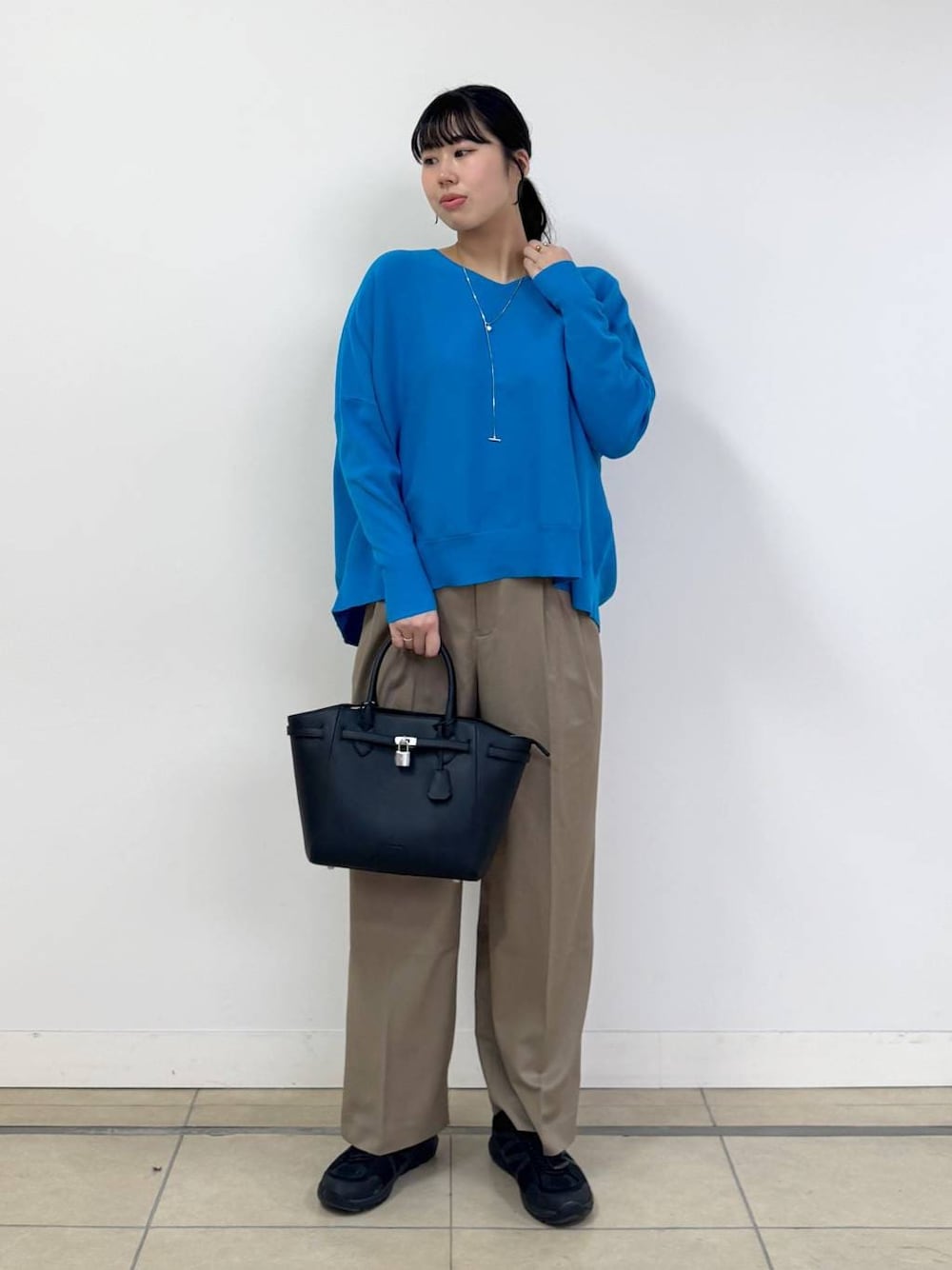 ブルー系のニット/セーター、ベージュ系のその他パンツ、ブラック系のハンドバッグを着用したレディースの冬コーディネートの1枚目の写真