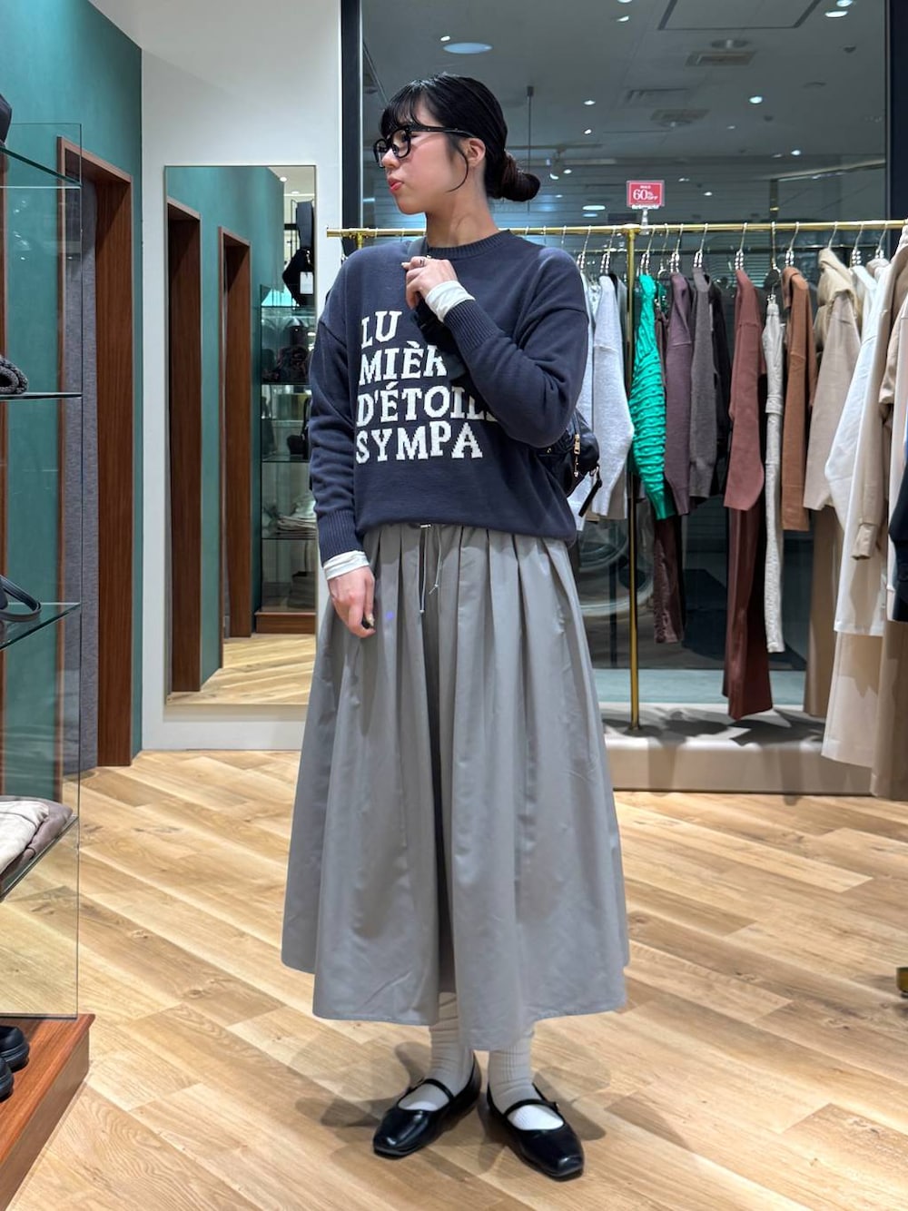 ホワイト系のTシャツ/カットソー、グレー系のニット/セーター、グレー系のスカートを着用したレディースの冬コーディネートの1枚目の写真