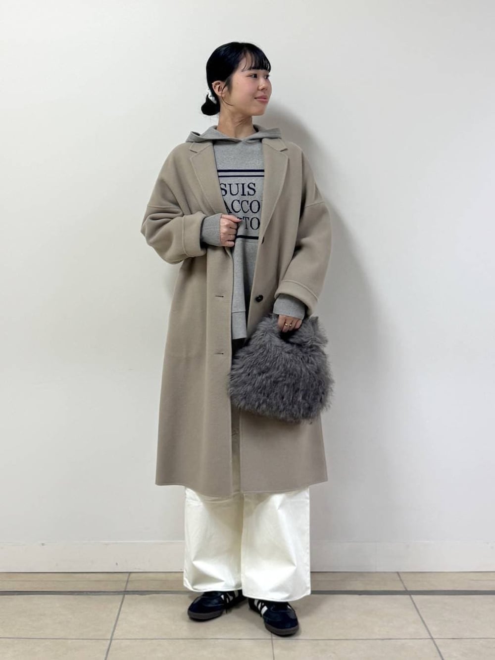 ベージュ系のニット/セーター、ブラウン系のトートバッグ、ベージュ系のチェスターコートを着用したレディースの秋コーディネートの1枚目の写真