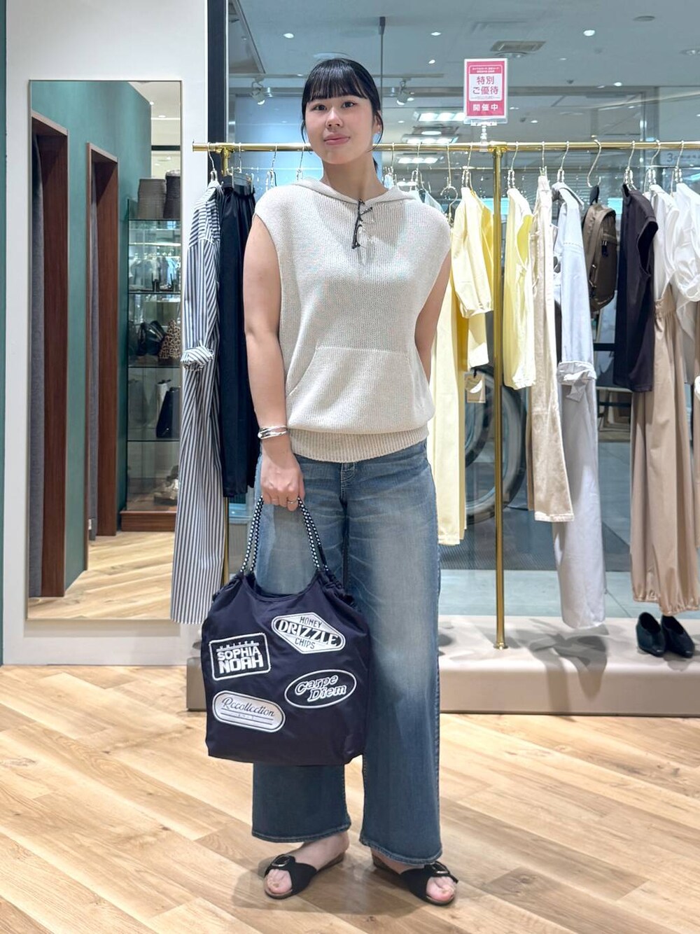ブルー系のデニムパンツ、ベージュ系のニット/セーター、ブルー系のトートバッグを着用したレディースの春コーディネートの1枚目の写真