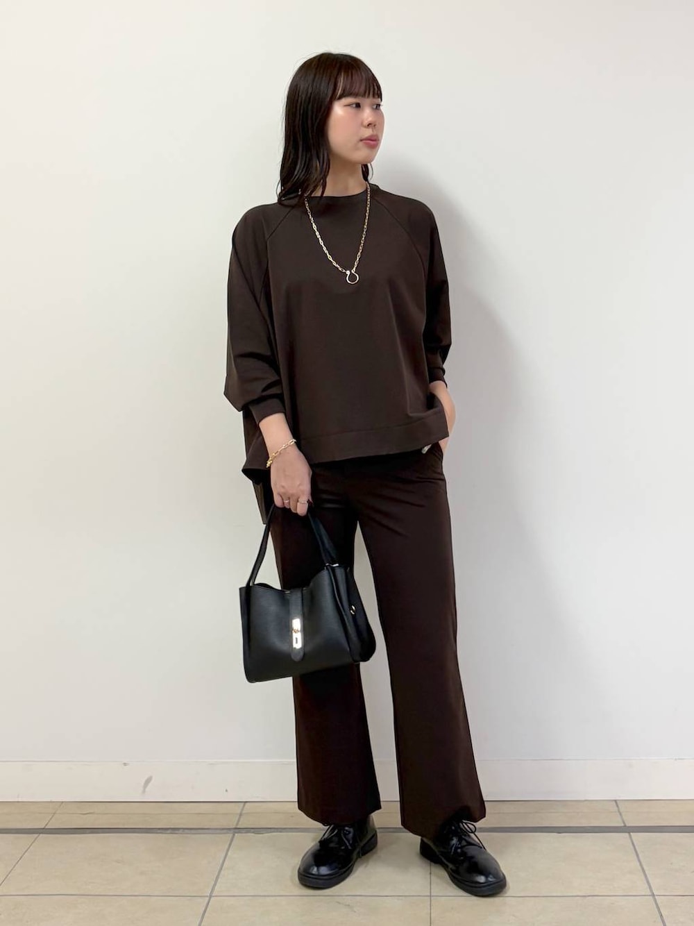 ブラック系のハンドバッグ、ブラウン系のTシャツ/カットソー、ブラウン系のその他パンツを着用したレディースの秋コーディネートの1枚目の写真