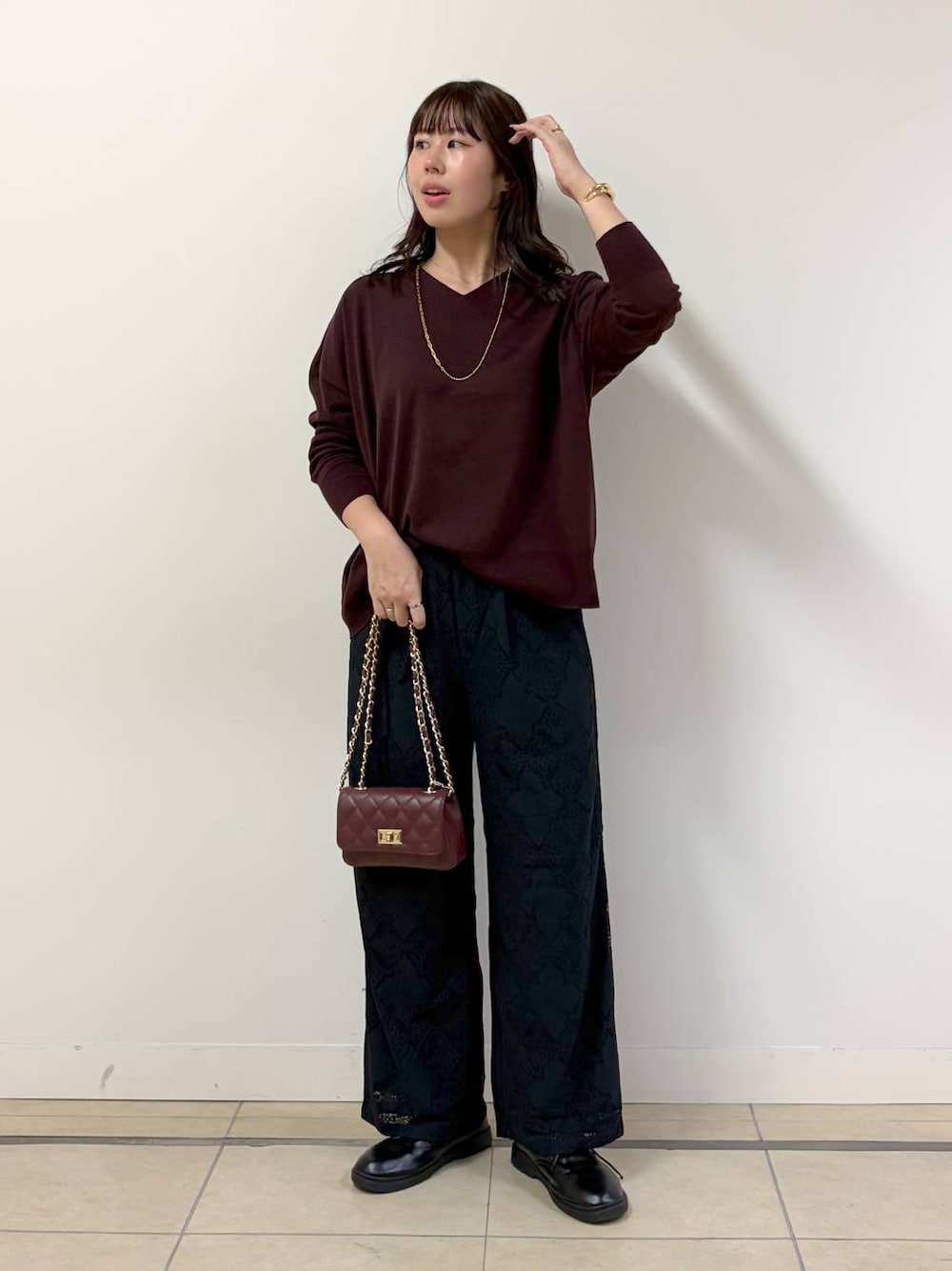ブラウン系のハンドバッグ、ブラック系のその他パンツ、レッド系のニット/セーターを着用したレディースの秋コーディネートの1枚目の写真
