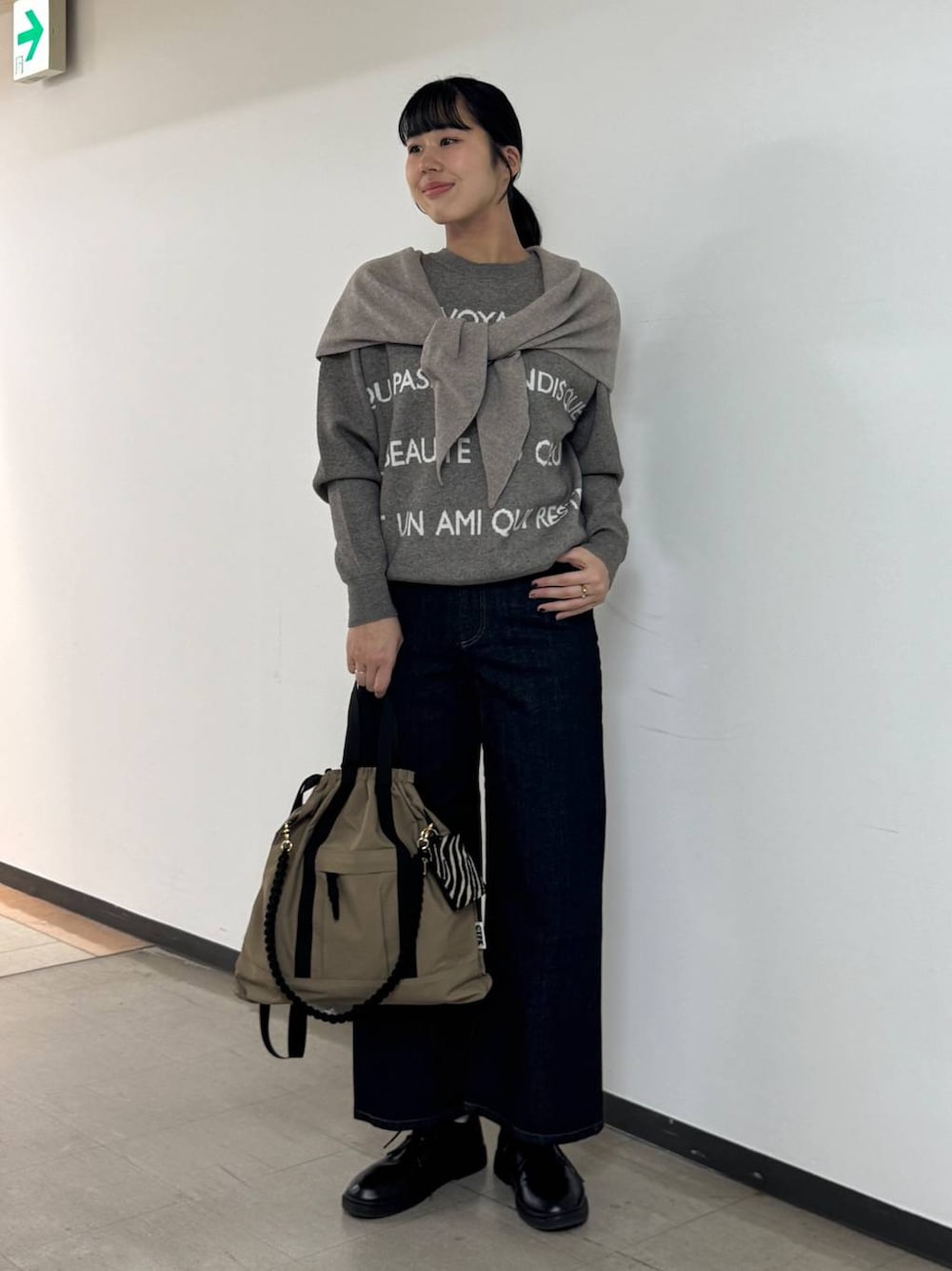 ブルー系のデニムパンツ、ブラウン系のバックパック/リュック、グレー系のニット/セーターを着用したレディースの秋コーディネートの1枚目の写真