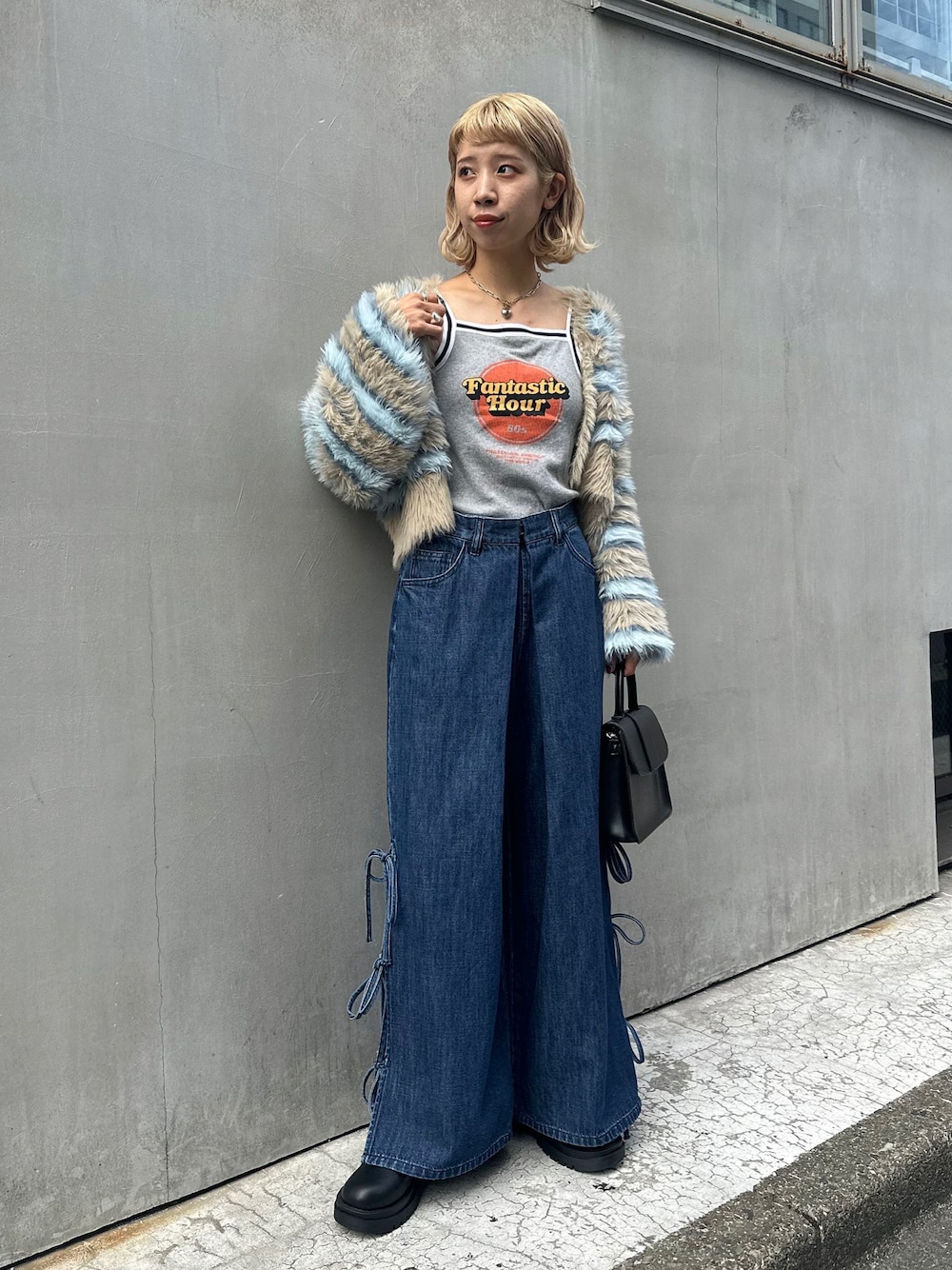 グレー系のキャミソール、グリーン系のカーディガン/ボレロ、ブルー系のデニムパンツを着用したレディースの秋コーディネートの1枚目の写真