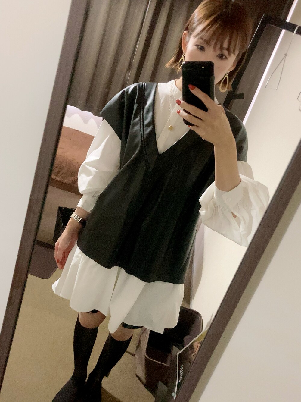 ブラック系のベスト、ホワイト系のシャツ/ブラウス、ゴールド系のピアス（両耳用）を着用したレディースの秋コーディネートの1枚目の写真