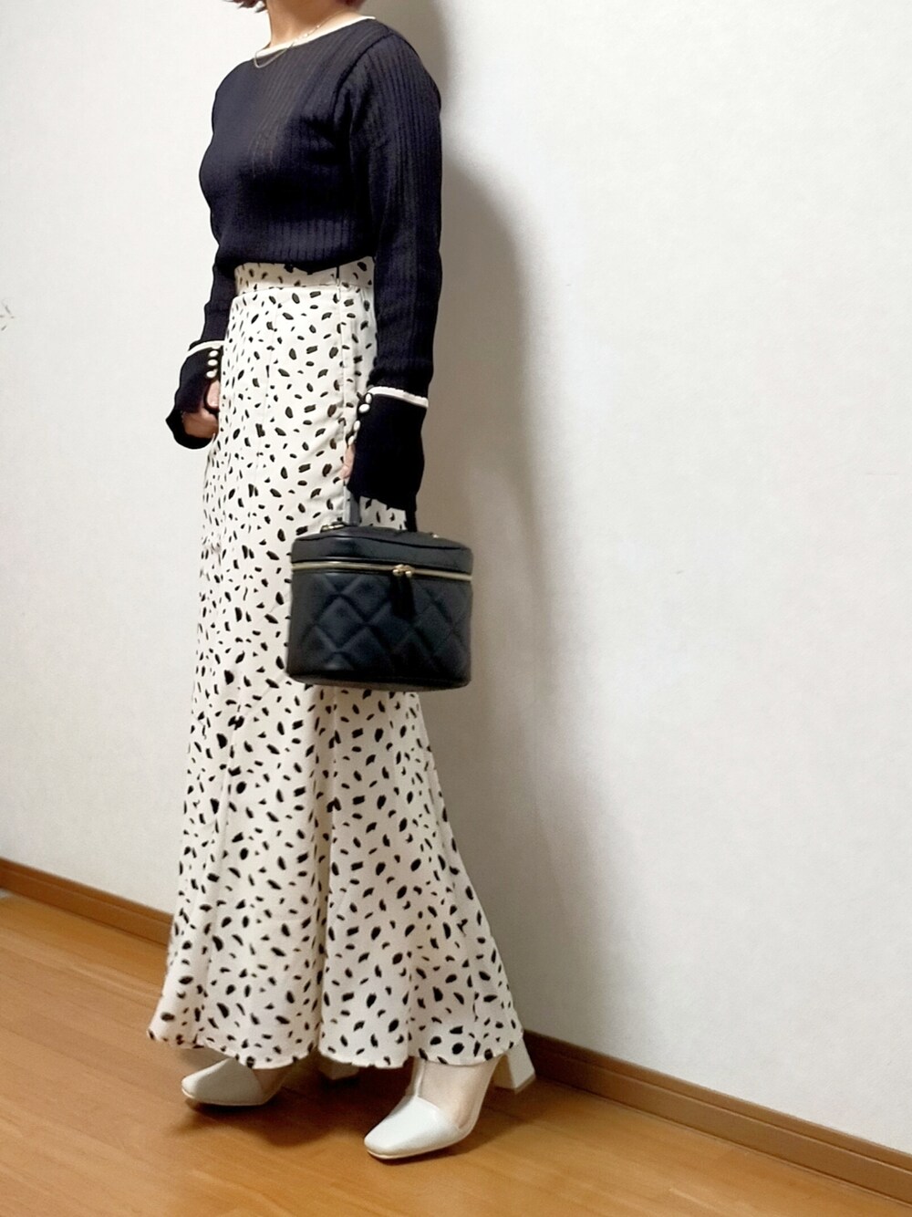 ブラック系のニット/セーター、ホワイト系のスカート、ブラック系のショルダーバッグを着用したレディースの春コーディネートの4枚目の写真