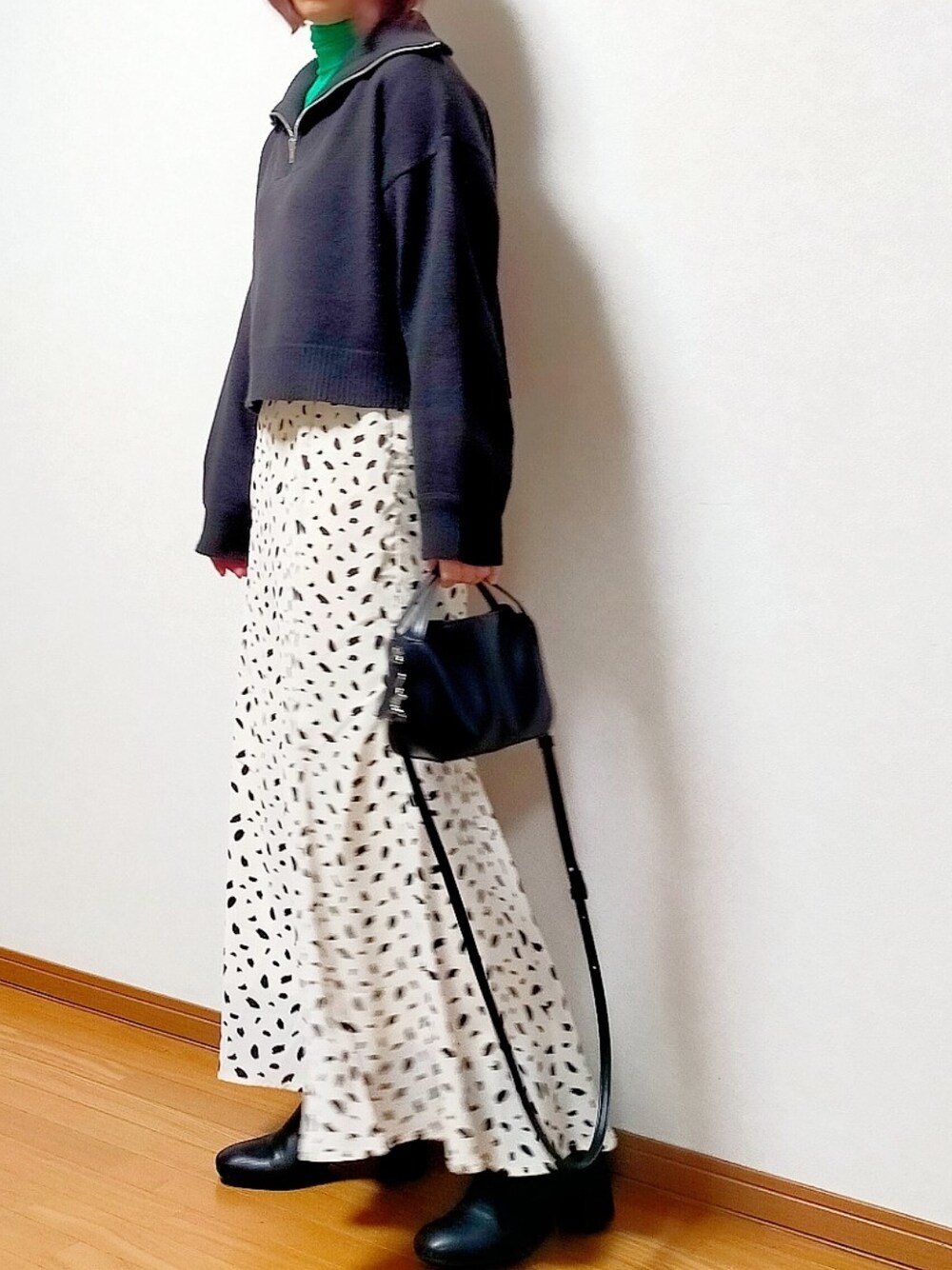 ブラック系のニット/セーター、グリーン系のTシャツ/カットソー、ホワイト系のスカートを着用したレディースの冬コーディネートの2枚目の写真