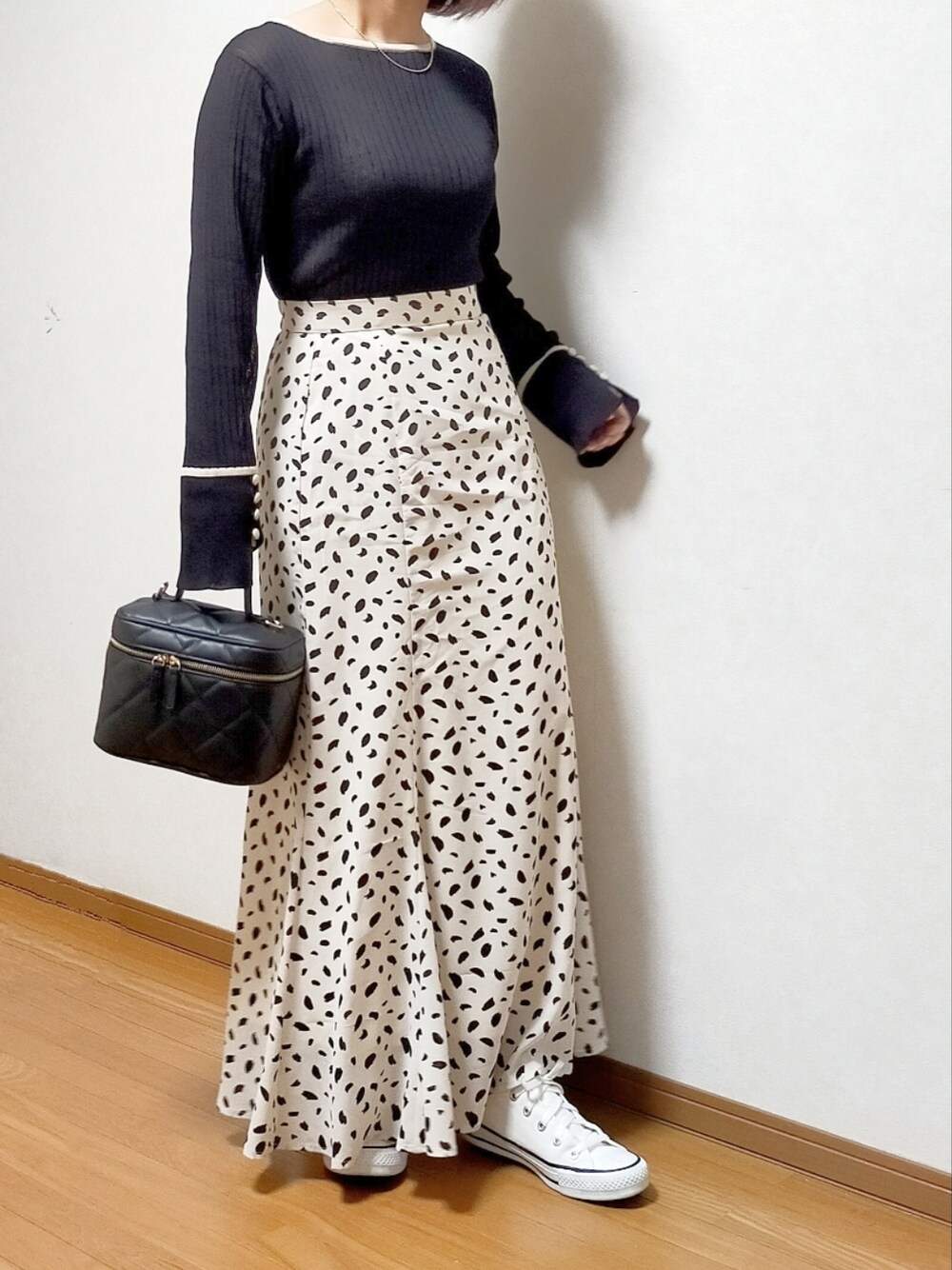 ブラック系のニット/セーター、ホワイト系のスカート、ブラック系のショルダーバッグを着用したレディースの春コーディネートの3枚目の写真