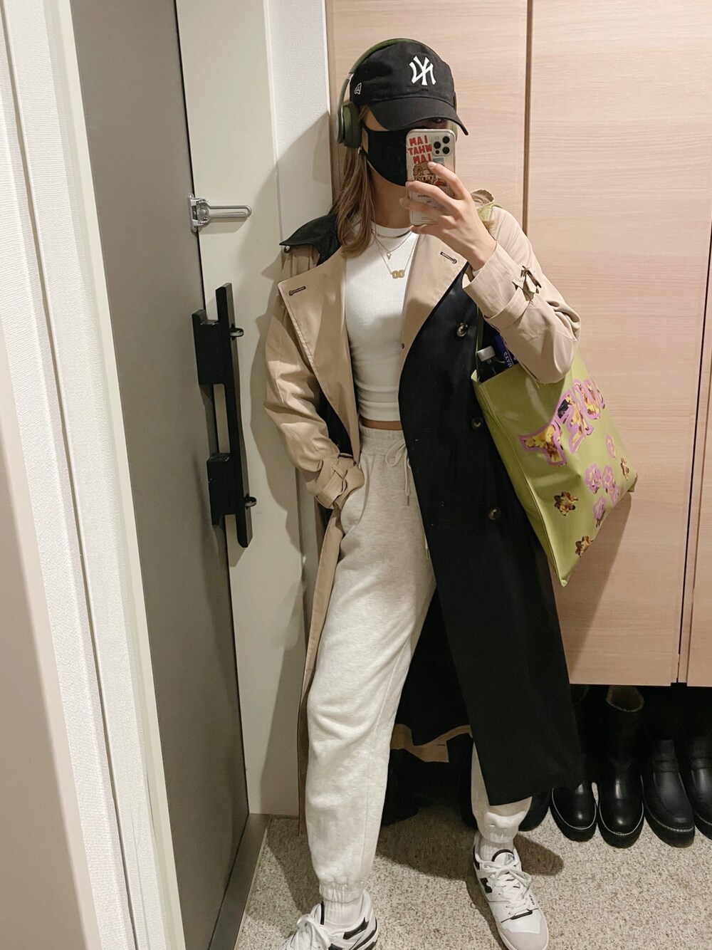 ホワイト系のトップス、ベージュ系のトレンチコート、グリーン系のトートバッグを着用したレディースの冬コーディネートの1枚目の写真