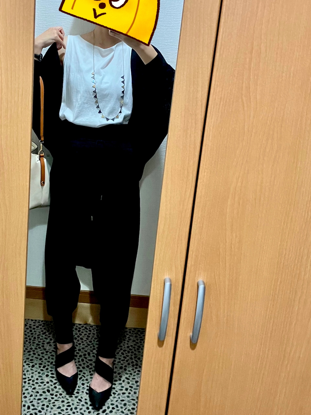 ブラック系のパンプス、ブラック系のカーディガン/ボレロ、ホワイト系のバッグを着用したレディースの夏コーディネートの1枚目の写真