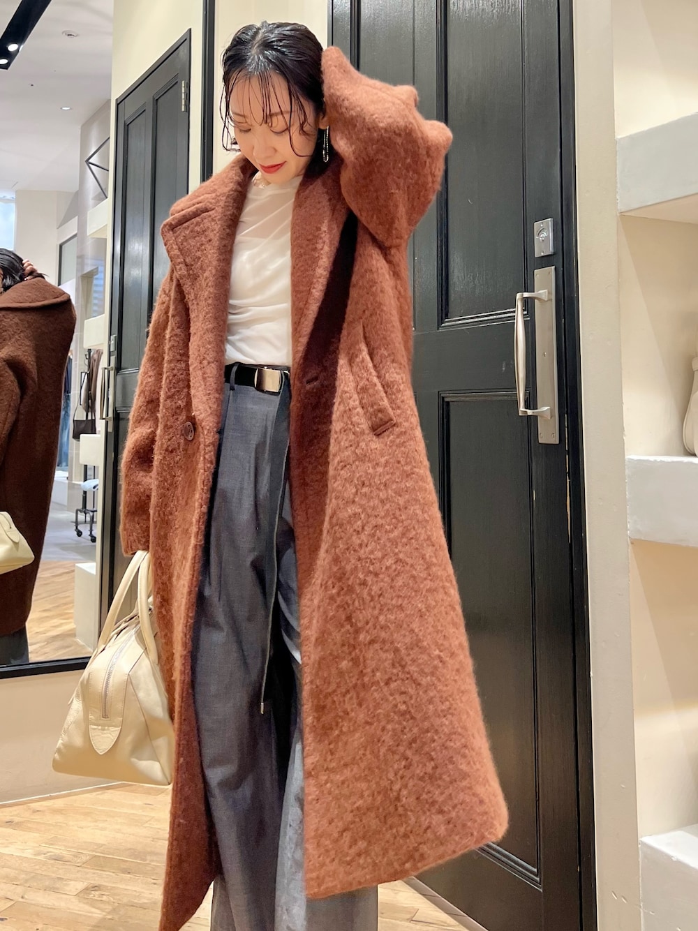 グレー系のスラックス、ホワイト系のTシャツ/カットソー、ベージュ系のトートバッグを着用したレディースの秋コーディネートの1枚目の写真