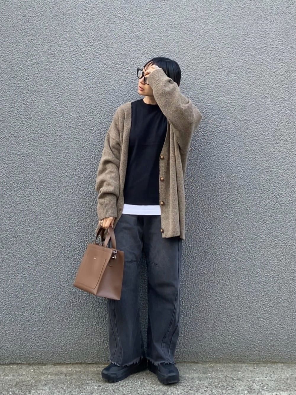 ブラウン系のカーディガン/ボレロ、ブラック系のニット/セーター、ブラック系のデニムパンツを着用したレディースの秋コーディネートの1枚目の写真