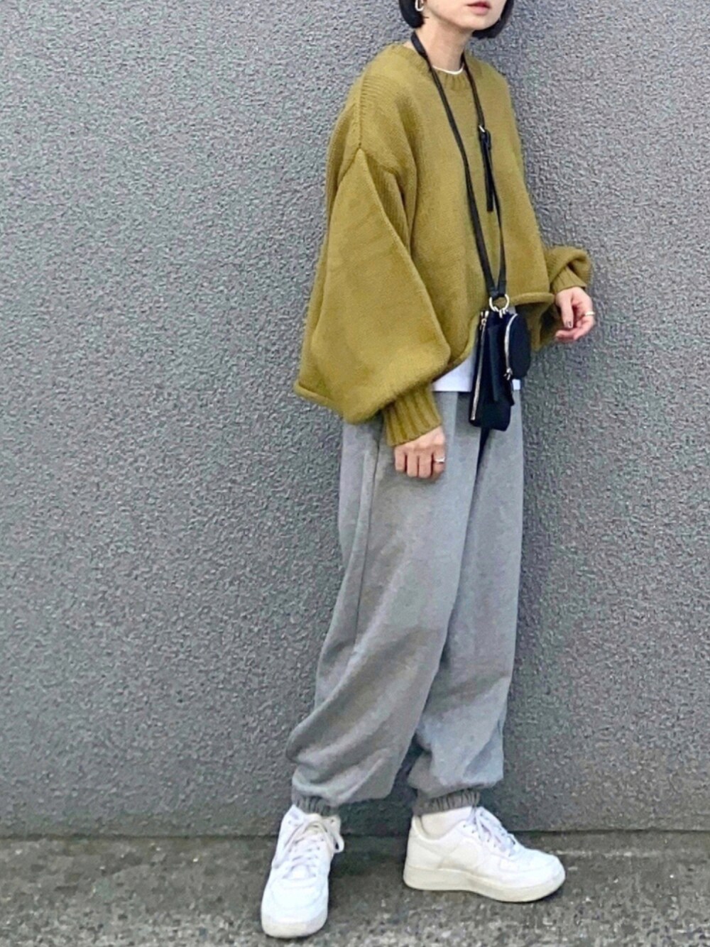 グリーン系のニット/セーター、グレー系のスウェットパンツ、ブラック系のショルダーバッグを着用したレディースの秋コーディネートの1枚目の写真