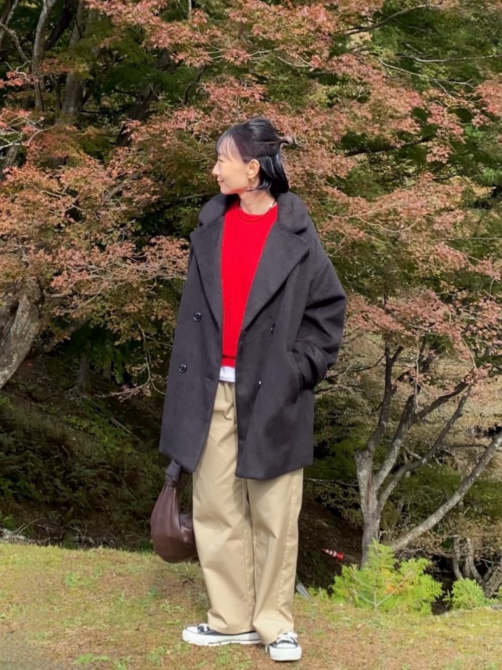 レッド系のニット/セーター、ブラック系のスニーカー、ブラック系のジャケット/アウターを着用したレディースの秋コーディネートの1枚目の写真