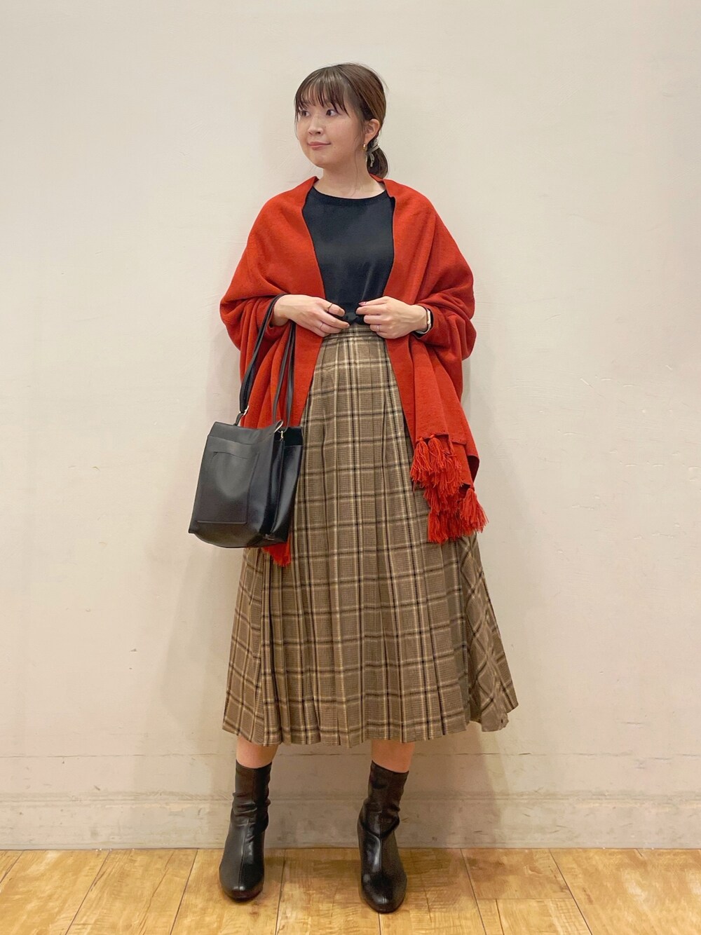 ブラック系のシャツ/ブラウス、オレンジ系のポンチョ、ベージュ系のスカートを着用したレディースの秋コーディネートの1枚目の写真