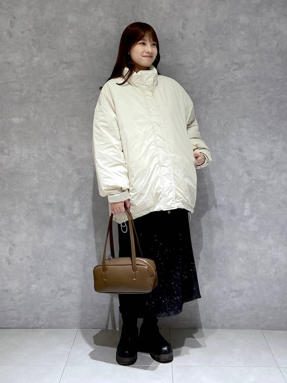 ホワイト系のダウンジャケット/コート、グレー系のスカート、ブラック系のブーツを着用したレディースの冬コーディネートの1枚目の写真