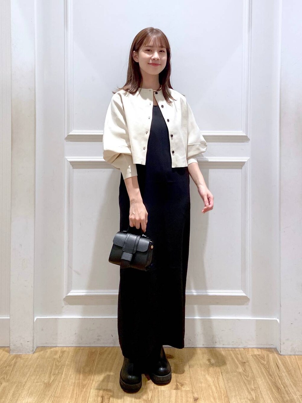 ホワイト系のワンピース、ブラック系のショルダーバッグ、ブラック系のブーツを着用したレディースの秋コーディネートの1枚目の写真