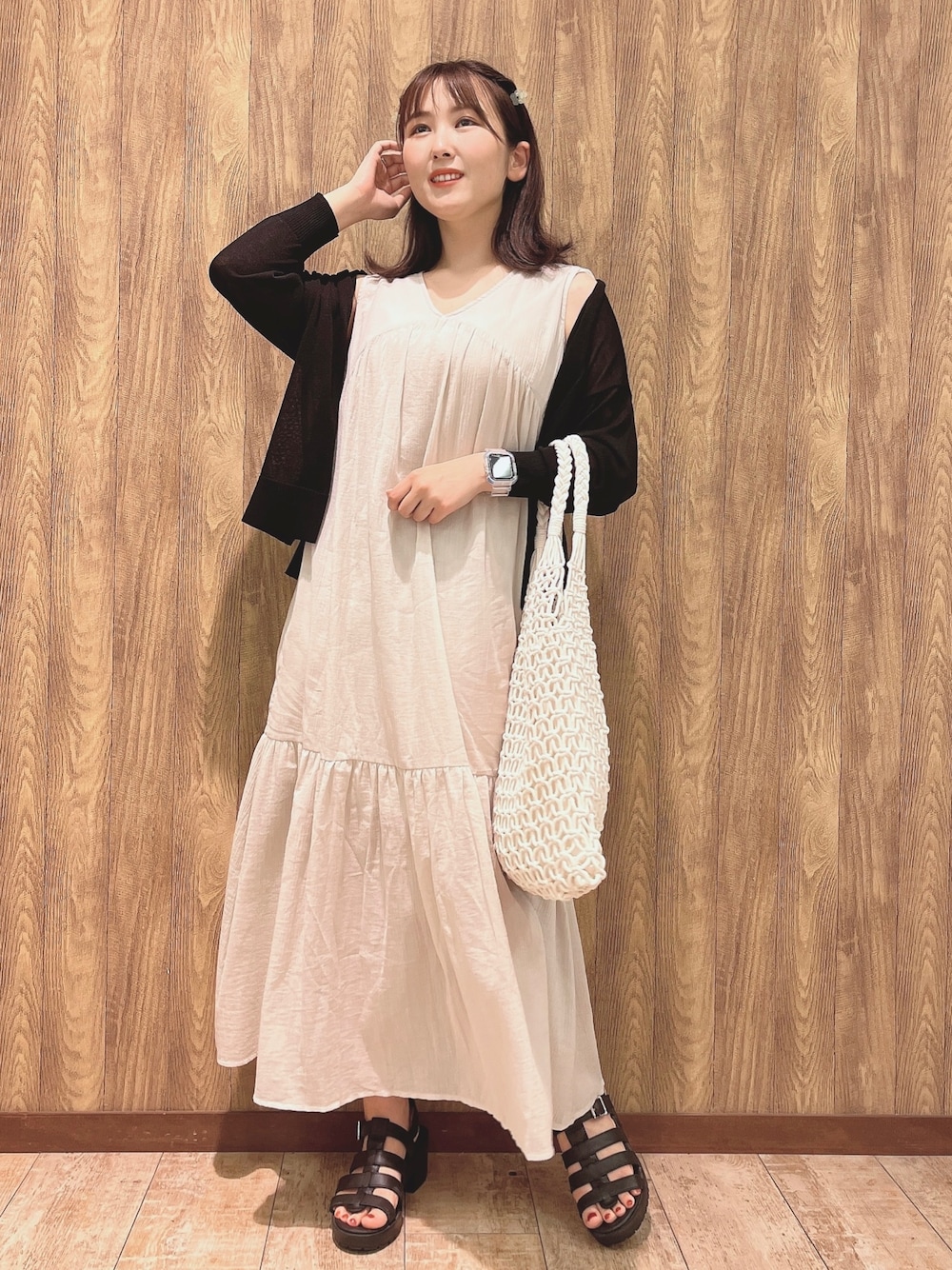 ブラック系のカーディガン/ボレロ、ベージュ系のワンピース、ブラック系のサンダルを着用したレディースの夏コーディネートの1枚目の写真