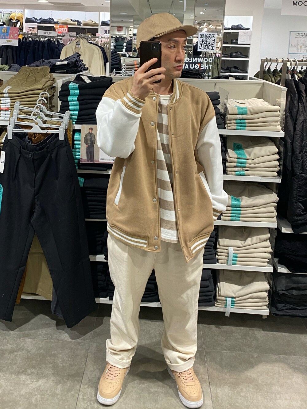 ベージュ系のスタジャン、ホワイト系のスラックス、ベージュ系のスニーカーを着用したメンズの秋コーディネートの1枚目の写真