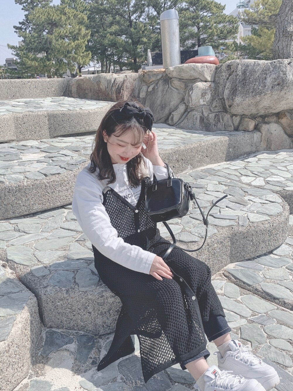 ホワイト系のトップス、ブラック系のワンピース、ブラック系のショルダーバッグを着用したレディースの夏コーディネートの1枚目の写真