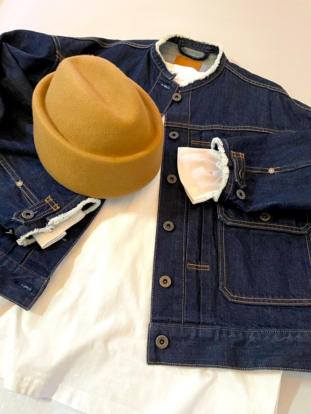 ブルー系のデニムジャケット、ホワイト系のTシャツ/カットソー、ベージュ系のハンチング/ベレー帽を着用したレディースの秋コーディネートの1枚目の写真