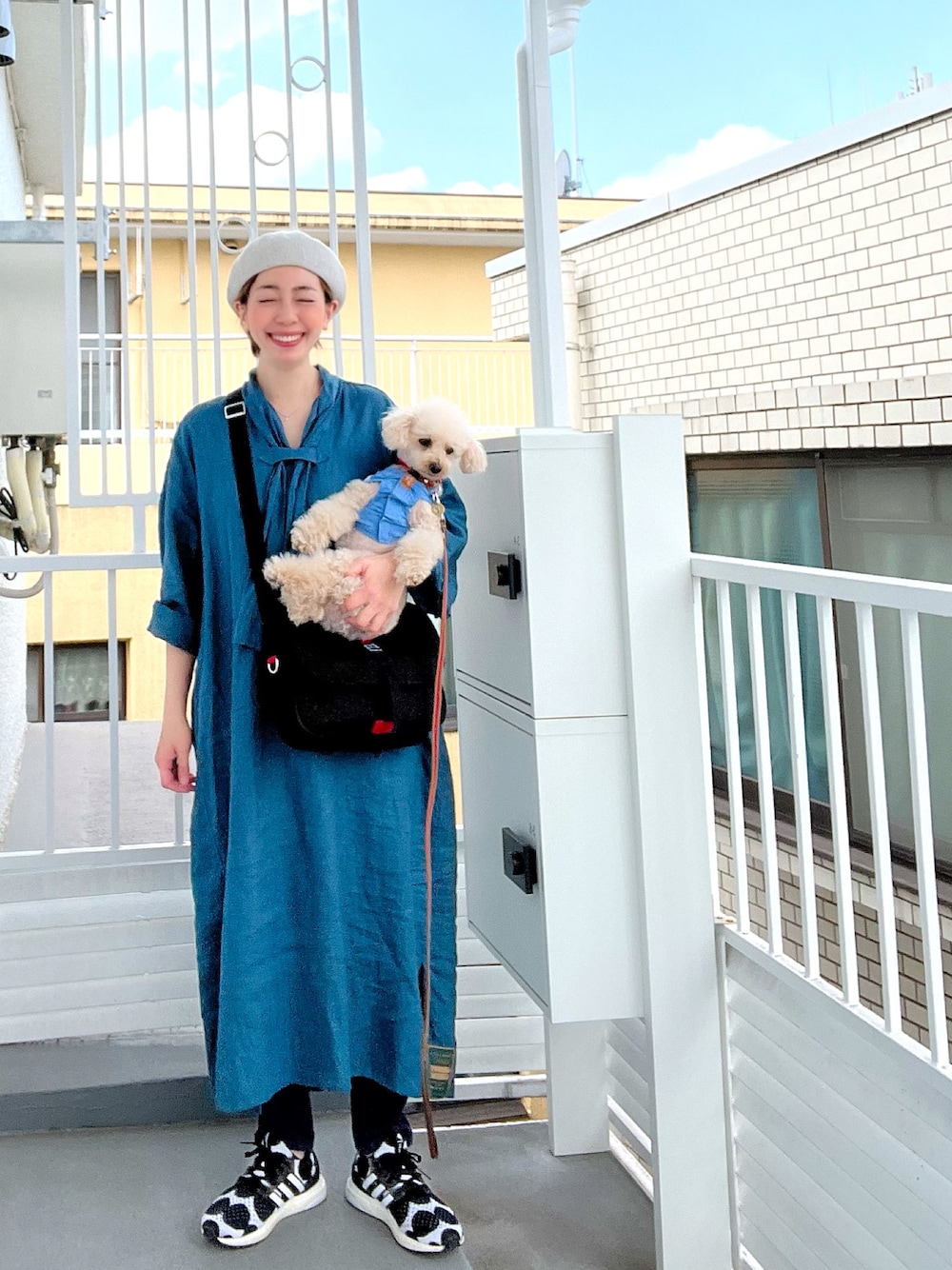 ブルー系のシャツワンピース、ブラック系のショルダーバッグ、ブラック系のスニーカーを着用したレディースの春コーディネートの1枚目の写真