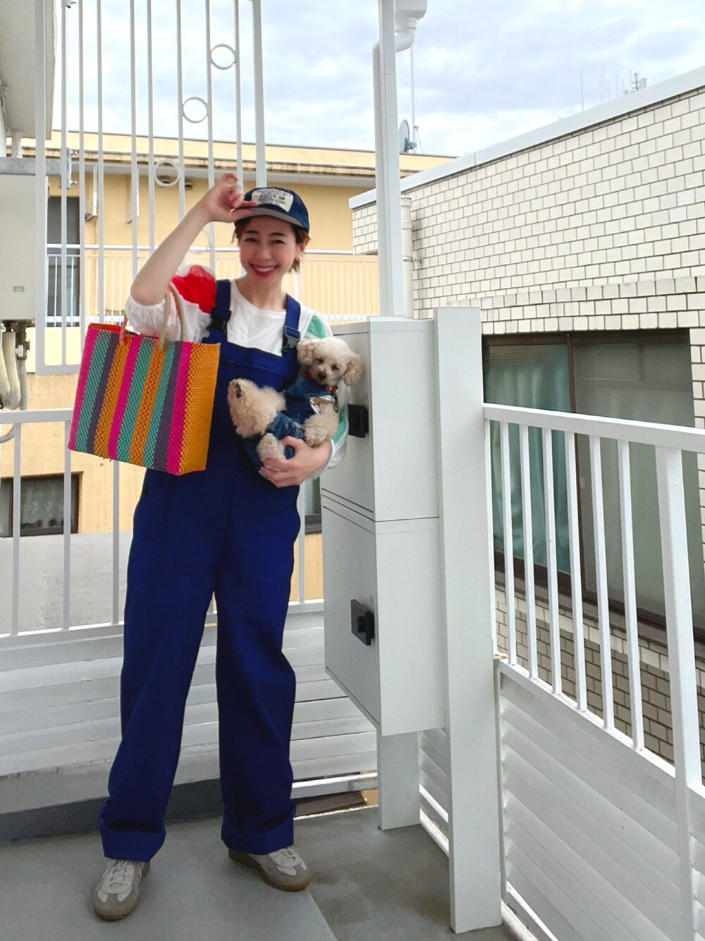 ブルー系のサロペット/オーバーオール、ホワイト系のTシャツ/カットソー、パープル系のカーディガン/ボレロを着用したレディースの春コーディネートの1枚目の写真