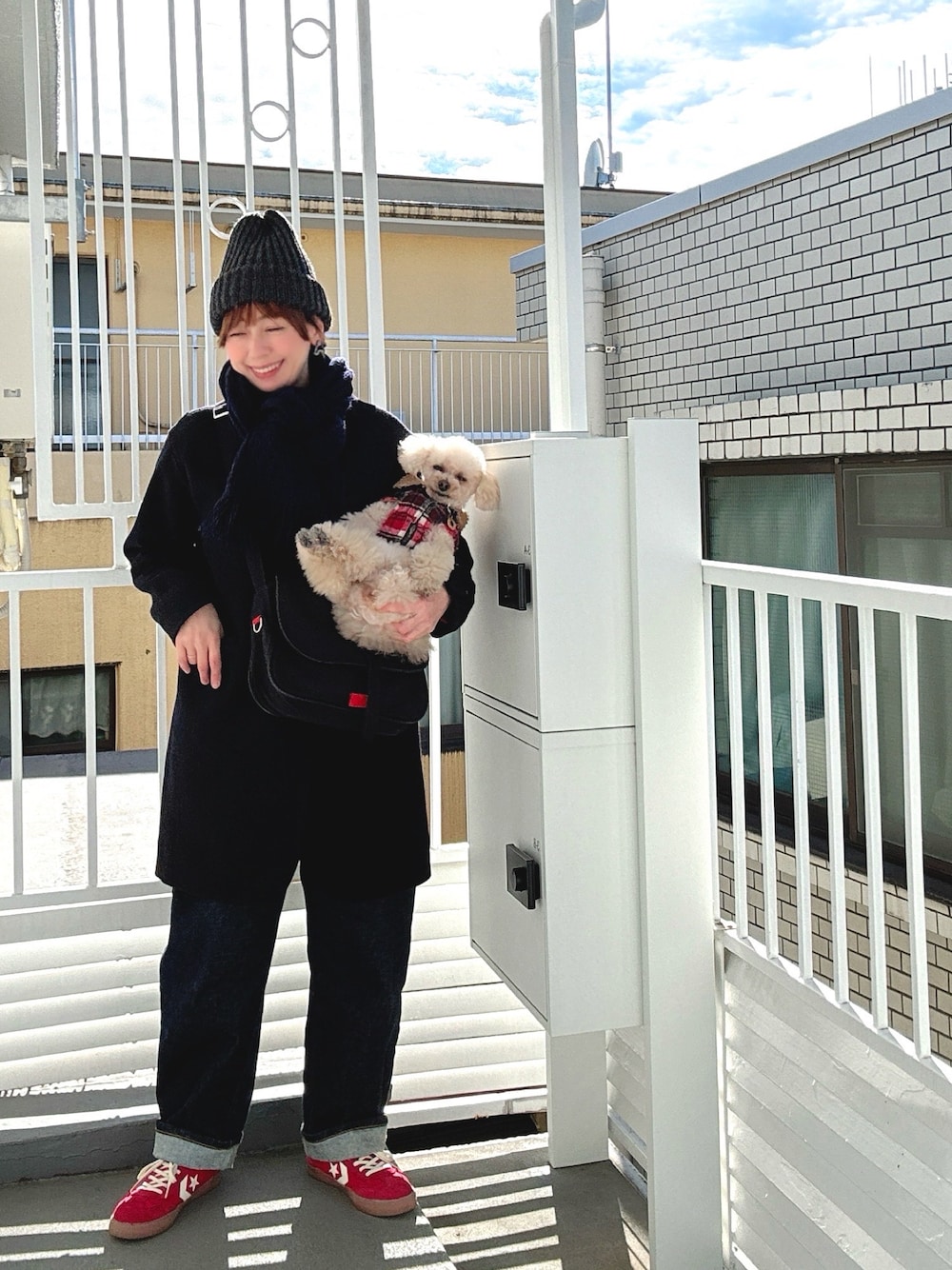 ブラック系のショルダーバッグ、ブルー系のノーカラーコート、ブルー系のデニムパンツを着用したレディースの冬コーディネートの1枚目の写真