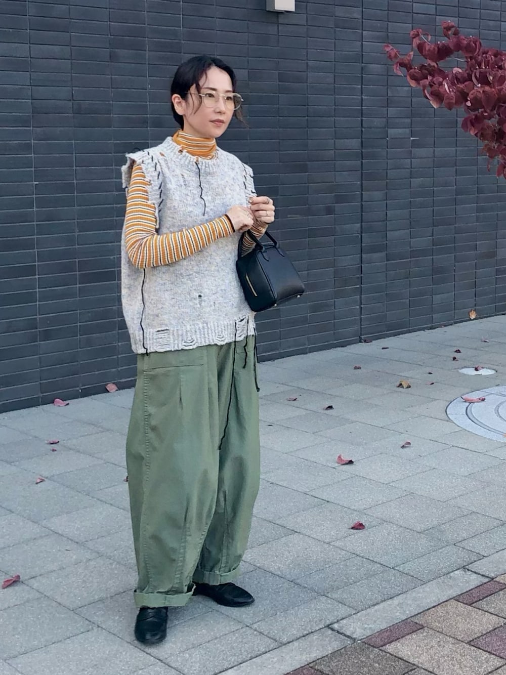 イエロー系のニット/セーター、グレー系のニット/セーター、グリーン系のその他パンツを着用したレディースの秋コーディネートの1枚目の写真