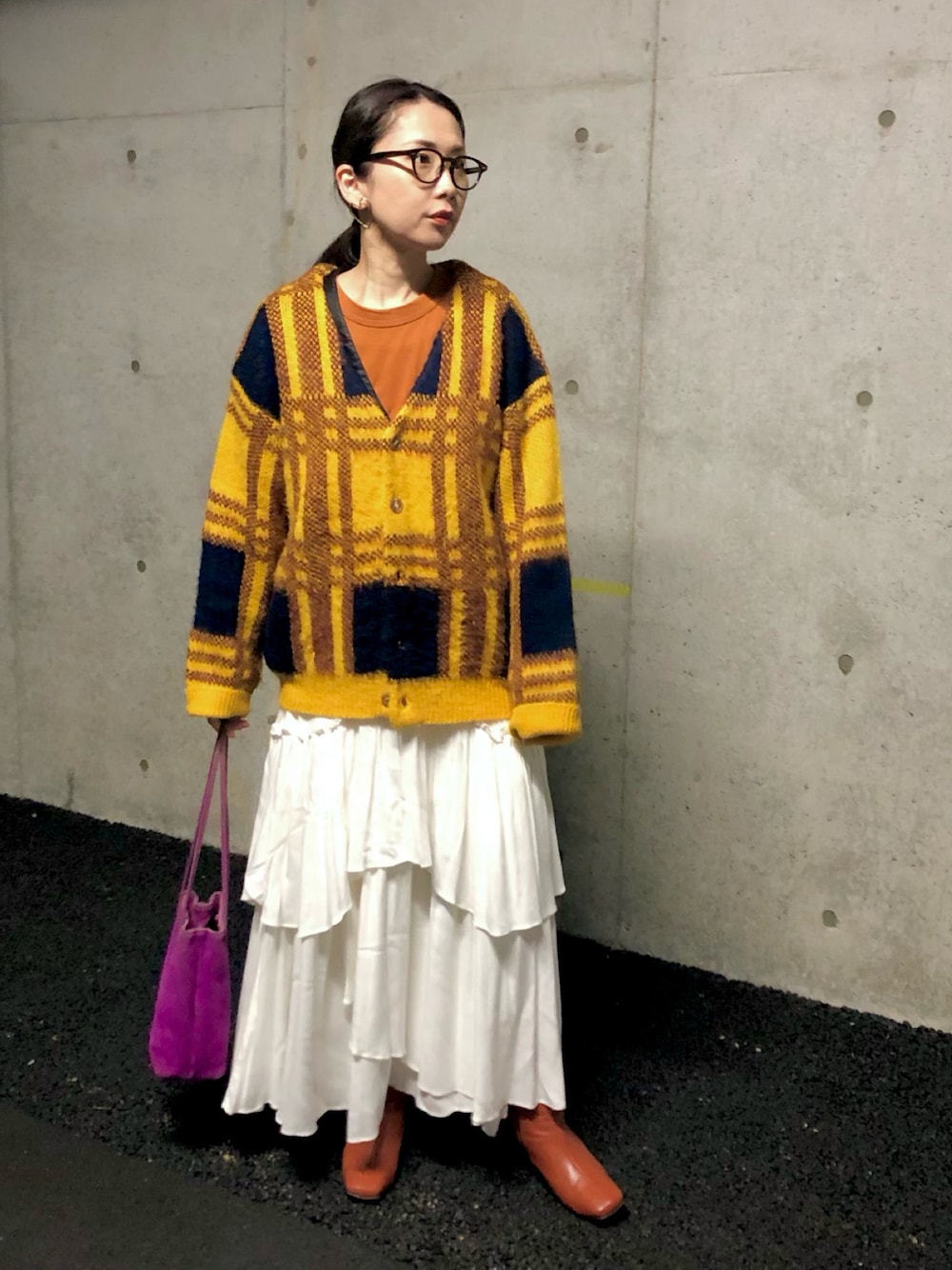 イエロー系のカーディガン/ボレロ、ブラウン系のTシャツ/カットソー、ホワイト系のスカートを着用したレディースの冬コーディネートの1枚目の写真