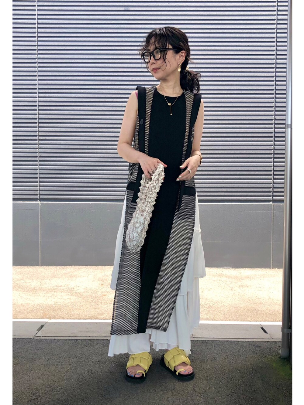 ブラック系のワンピース、ホワイト系のスカート、ベージュ系のハンドバッグを着用したレディースの夏コーディネートの1枚目の写真