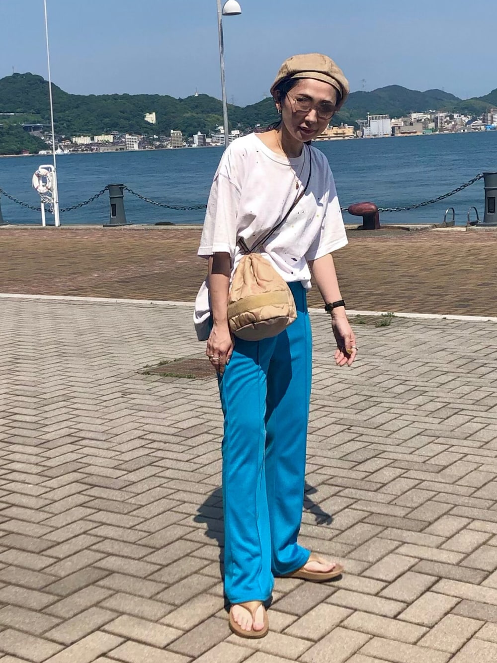 ホワイト系のTシャツ/カットソー、ブルー系のスラックス、ベージュ系のショルダーバッグを着用したレディースの夏コーディネートの1枚目の写真