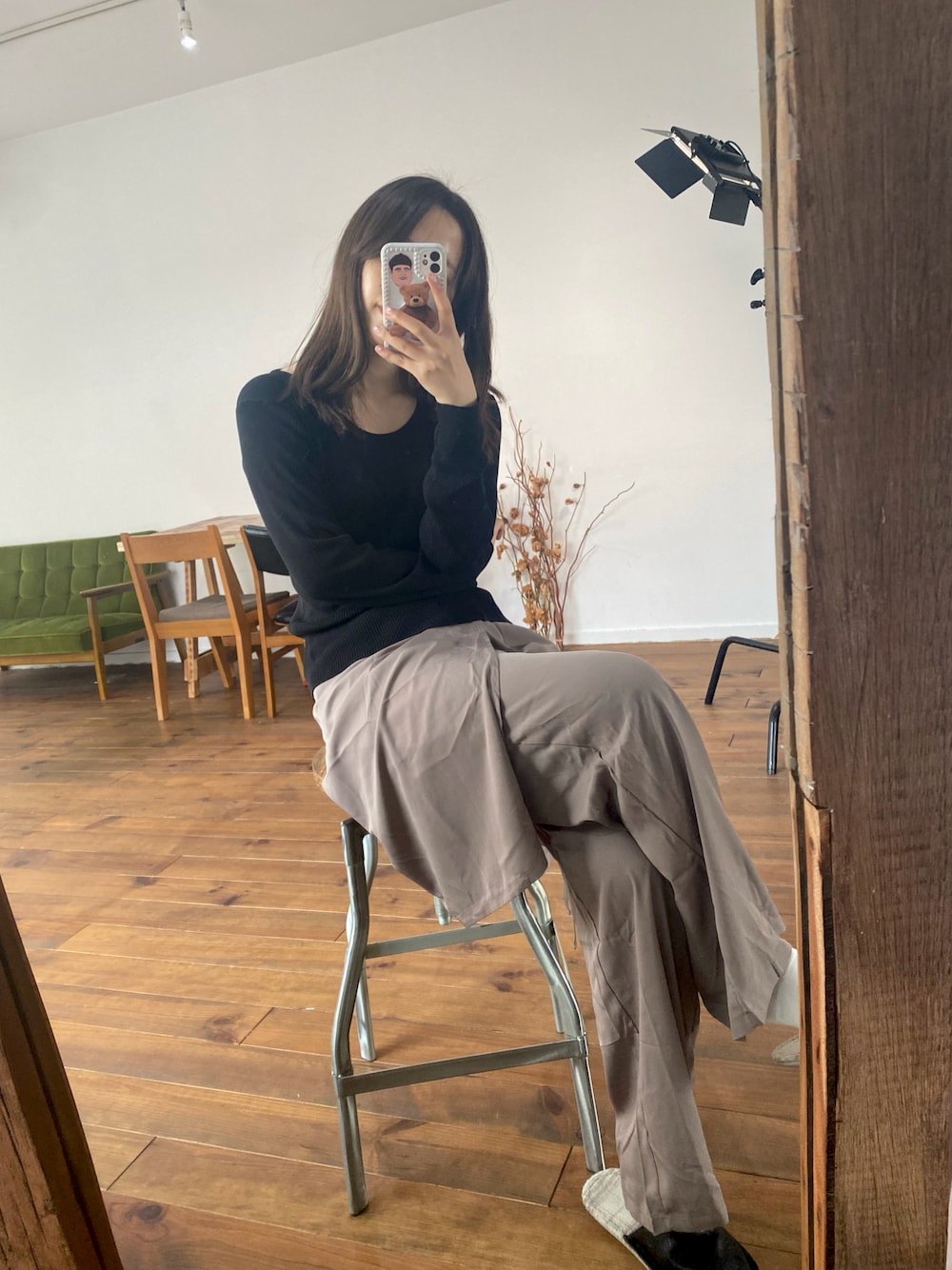 ブラック系のニット/セーター、ベージュ系のスラックス、ゴールド系のピアス（両耳用）を着用したレディースの春コーディネートの1枚目の写真