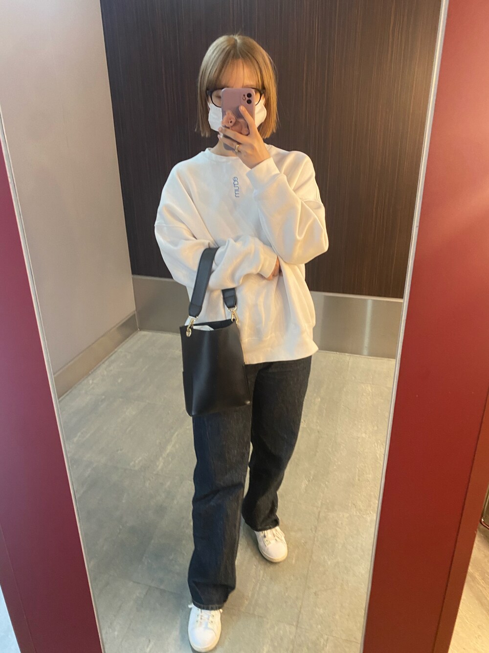 ブラック系のショルダーバッグ、ホワイト系のスウェット、ブルー系のデニムパンツを着用したレディースの春コーディネートの1枚目の写真