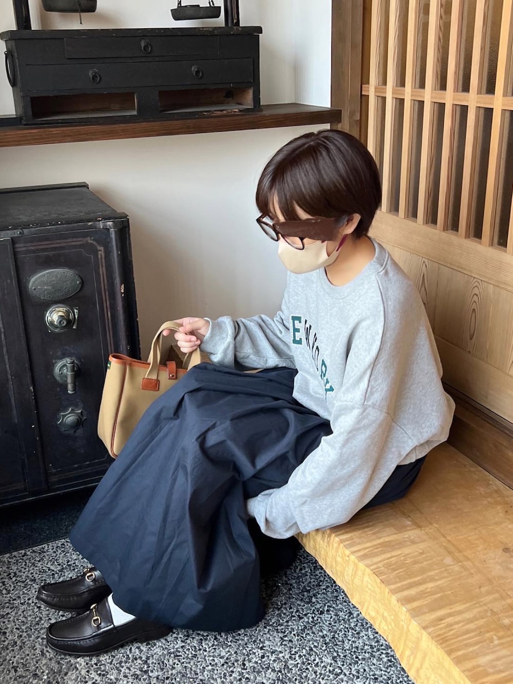 グリーン系のトートバッグを着用したレディースの秋コーディネートの1枚目の写真