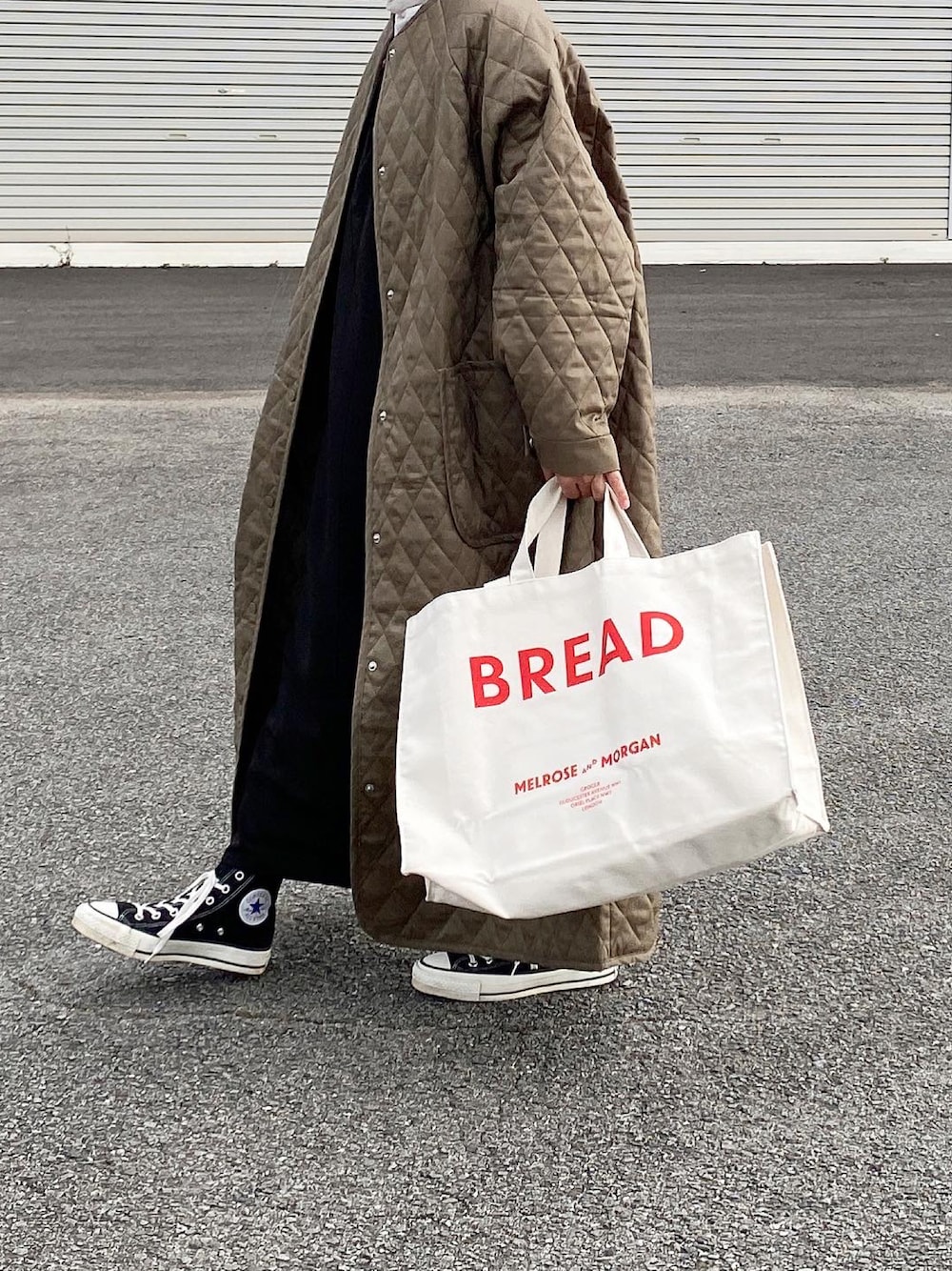 グリーン系のノーカラーコート、ブラック系のワンピース、ブラック系のスニーカーを着用したレディースの秋コーディネートの1枚目の写真