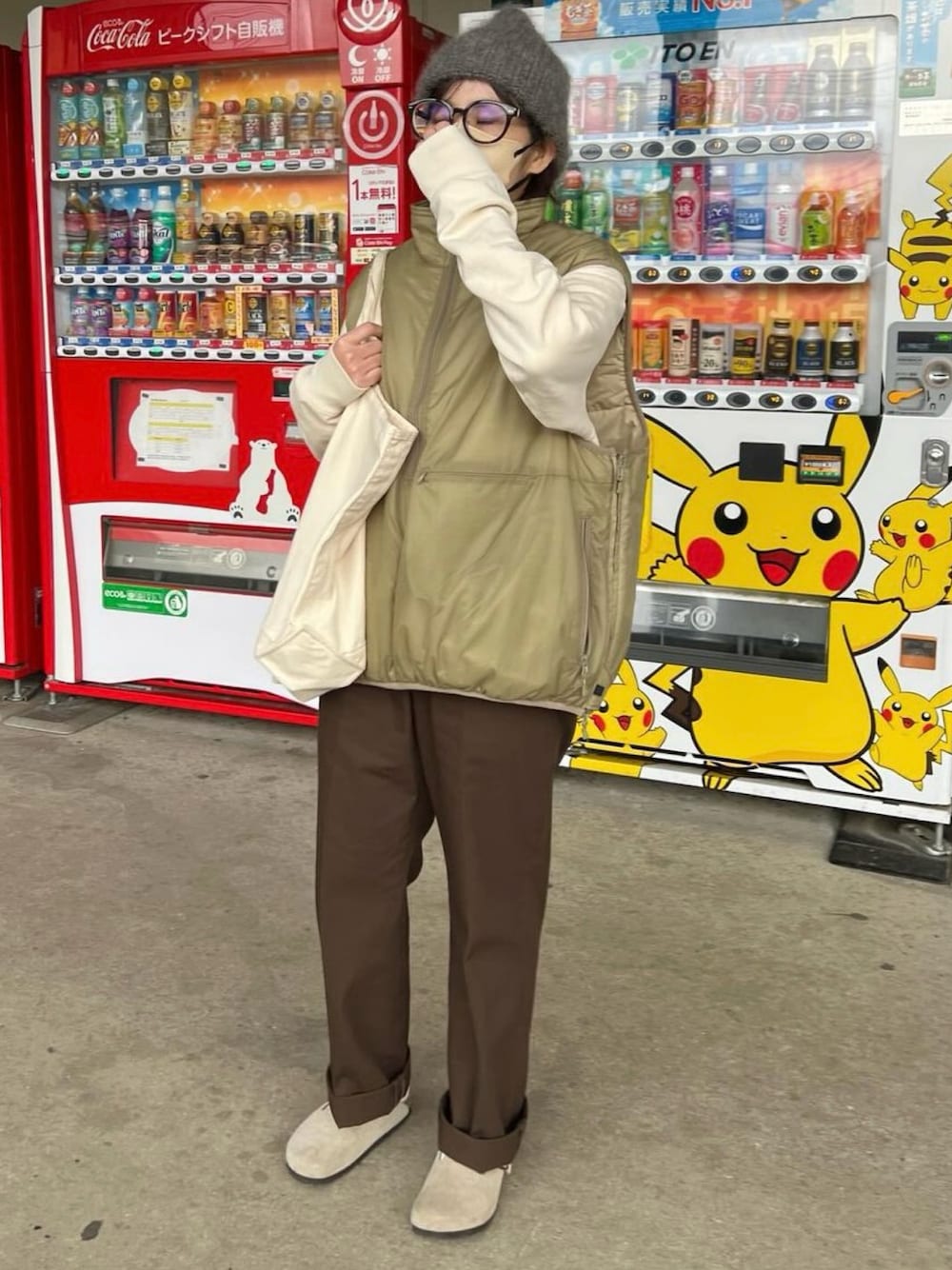 ベージュ系のベスト、ブラウン系のチノパンツ、ベージュ系のサンダルを着用したレディースの冬コーディネートの1枚目の写真