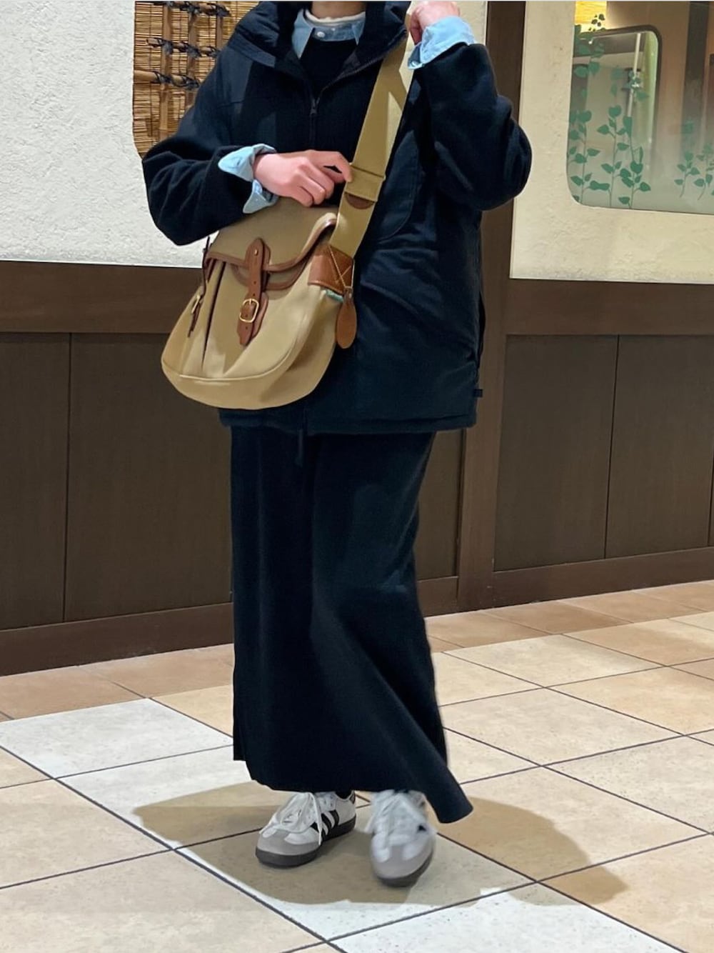 グリーン系のショルダーバッグ、ブラック系のベスト、ブルー系のシャツ/ブラウスを着用したレディースの冬コーディネートの1枚目の写真