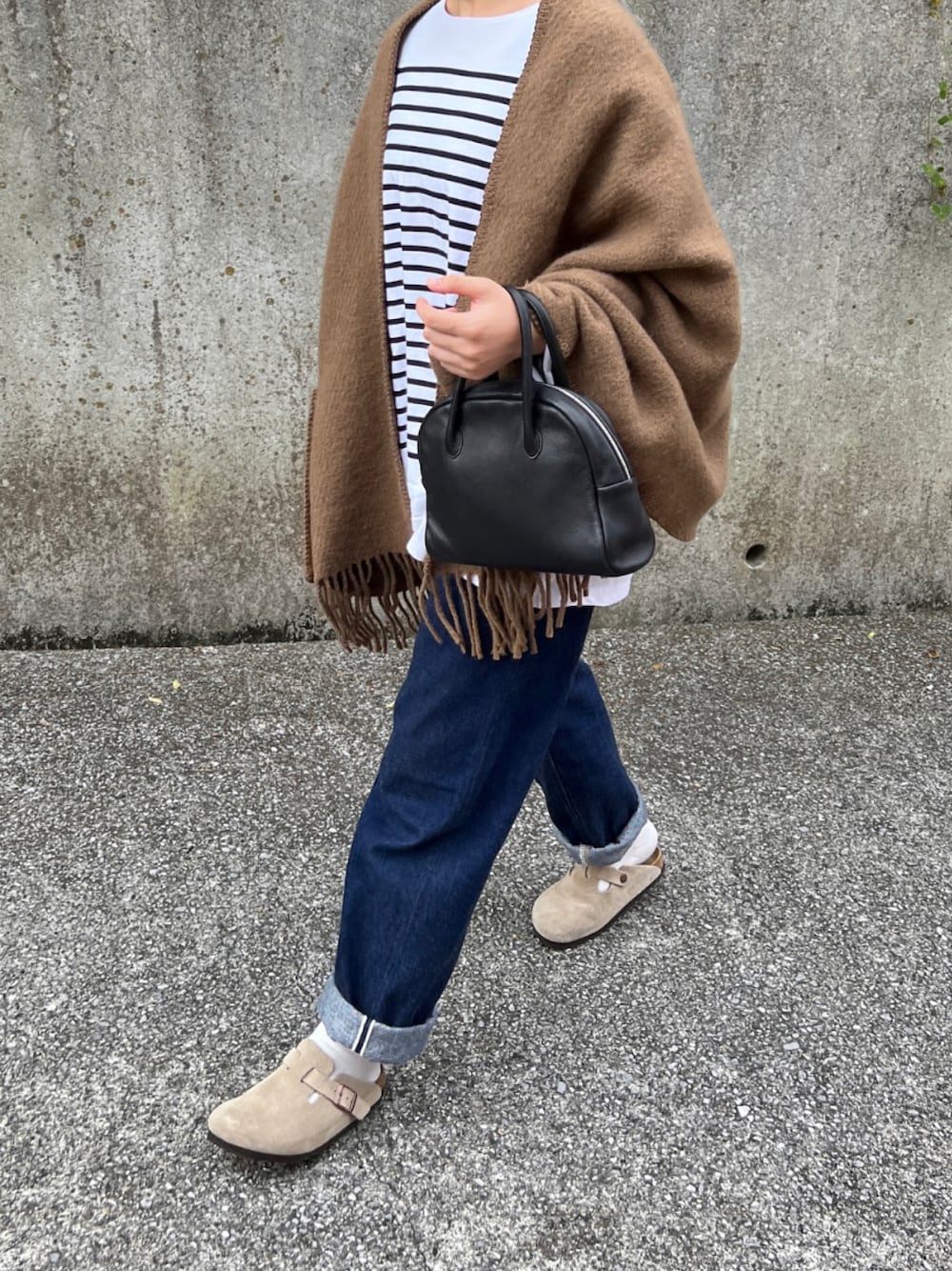 ブラック系のバッグ、ブルー系のデニムパンツ、ベージュ系のサンダルを着用したレディースの秋コーディネートの1枚目の写真