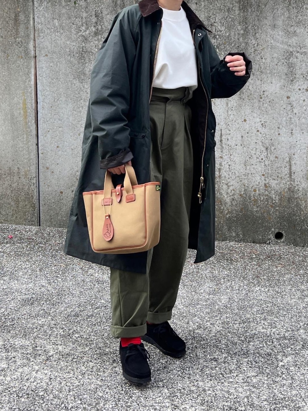 グリーン系のトートバッグ、ブラック系のモカシン/デッキシューズ、グリーン系のステンカラーコートを着用したレディースの冬コーディネートの1枚目の写真