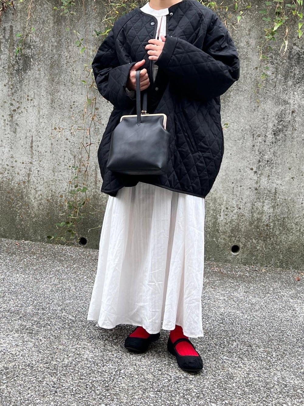 ブラック系のノーカラーコート、ホワイト系のワンピースを着用したレディースの秋コーディネートの1枚目の写真