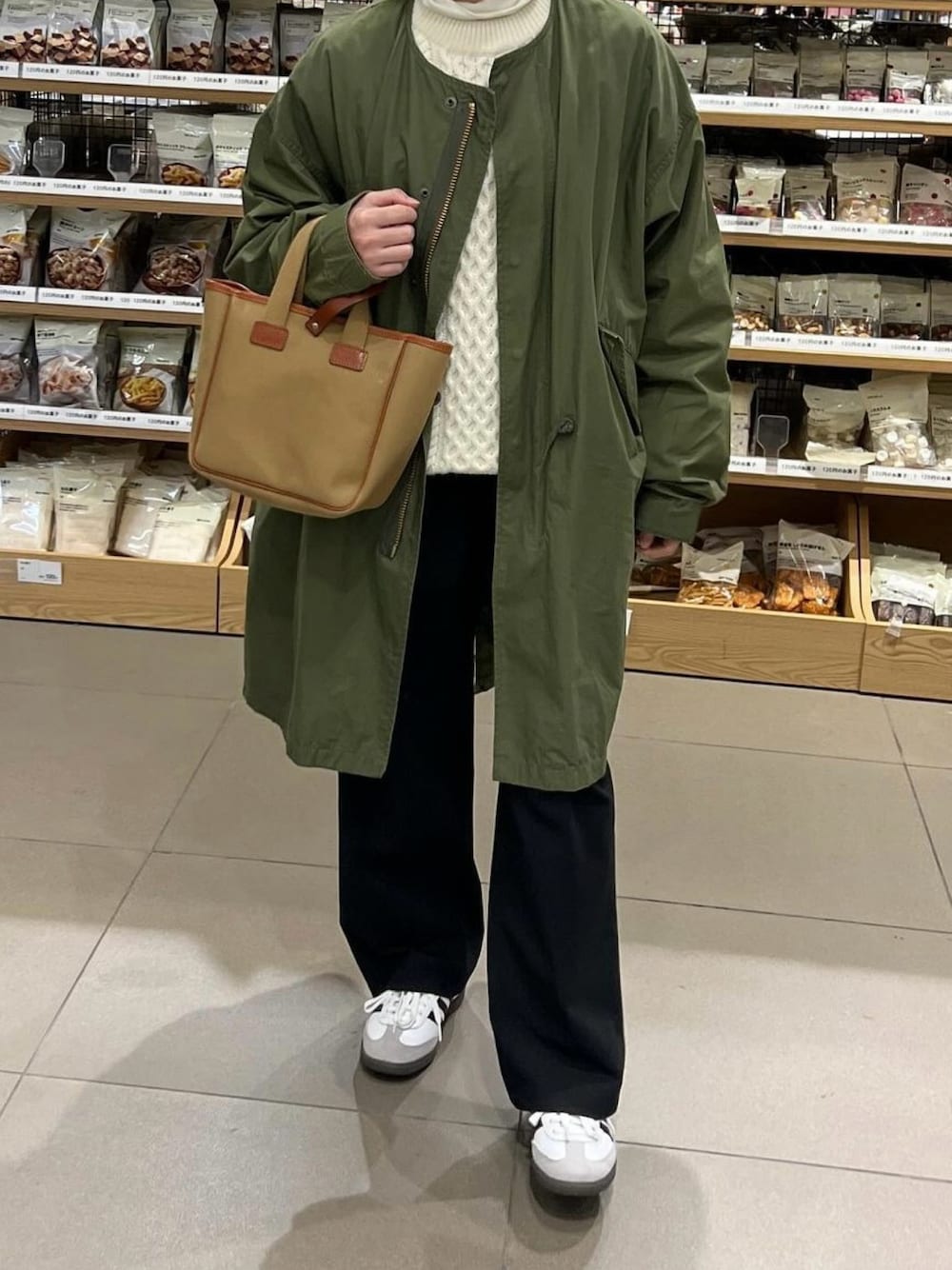 グリーン系のトートバッグ、ホワイト系のスニーカーを着用したレディースの冬コーディネートの1枚目の写真