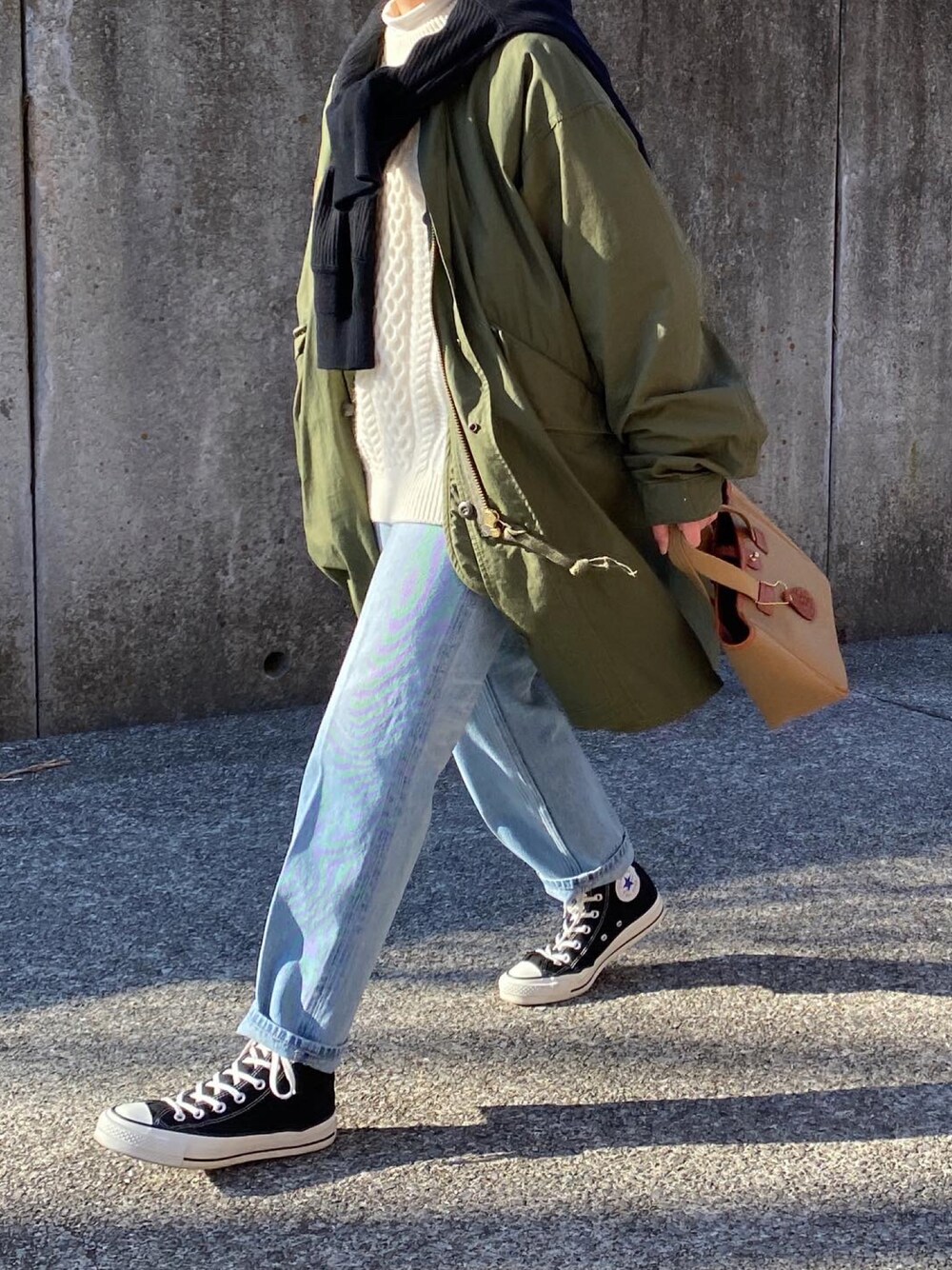 グリーン系のミリタリージャケット、ブルー系のデニムパンツ、グリーン系のトートバッグを着用したレディースの冬コーディネートの1枚目の写真