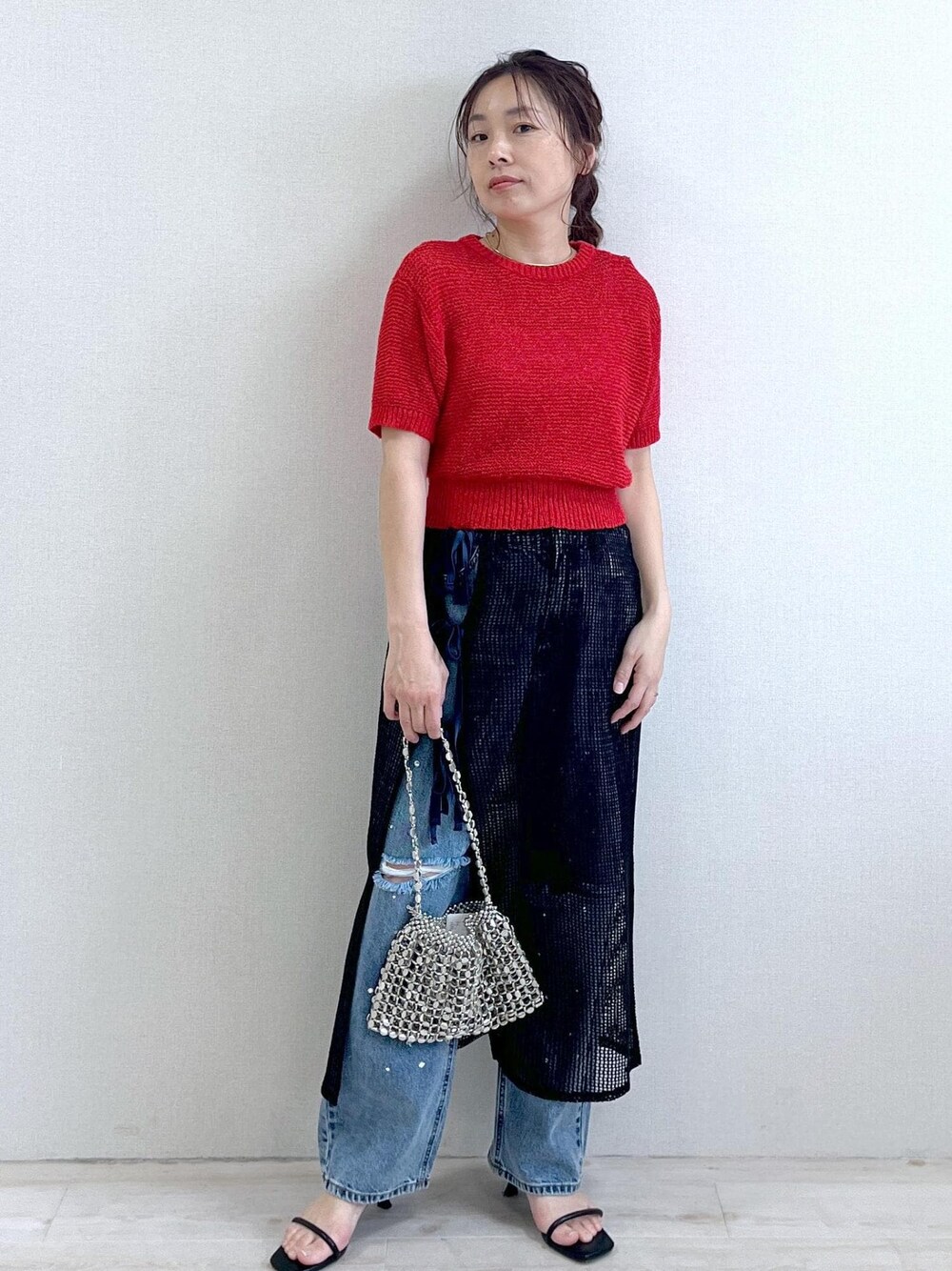 シルバー系のショルダーバッグ、ブルー系のデニムパンツ、ブラック系のサンダルを着用したレディースの春コーディネートの1枚目の写真