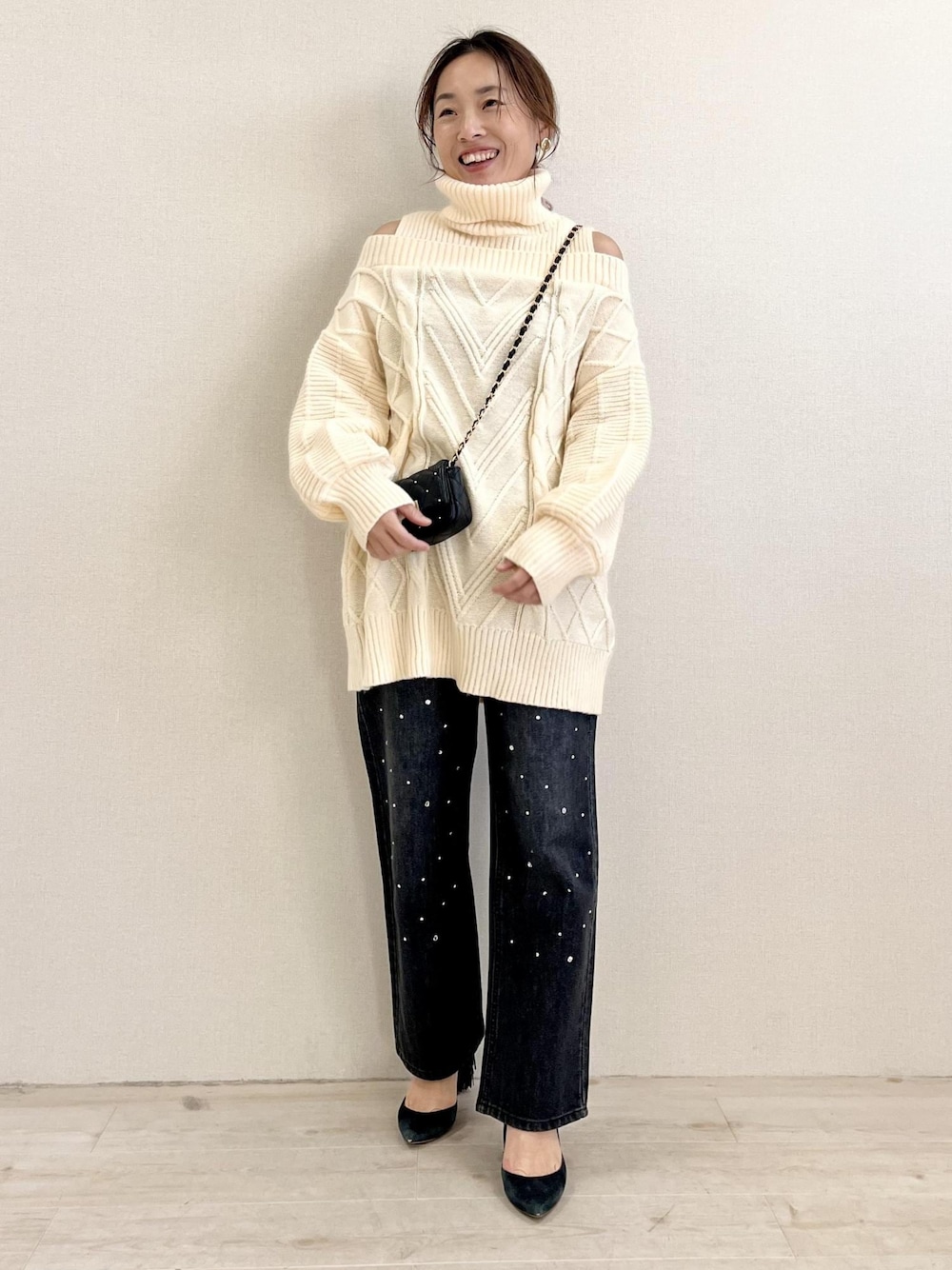 ブラック系のデニムパンツ、ホワイト系のワンピース、ブラック系のショルダーバッグを着用したレディースの冬コーディネートの1枚目の写真