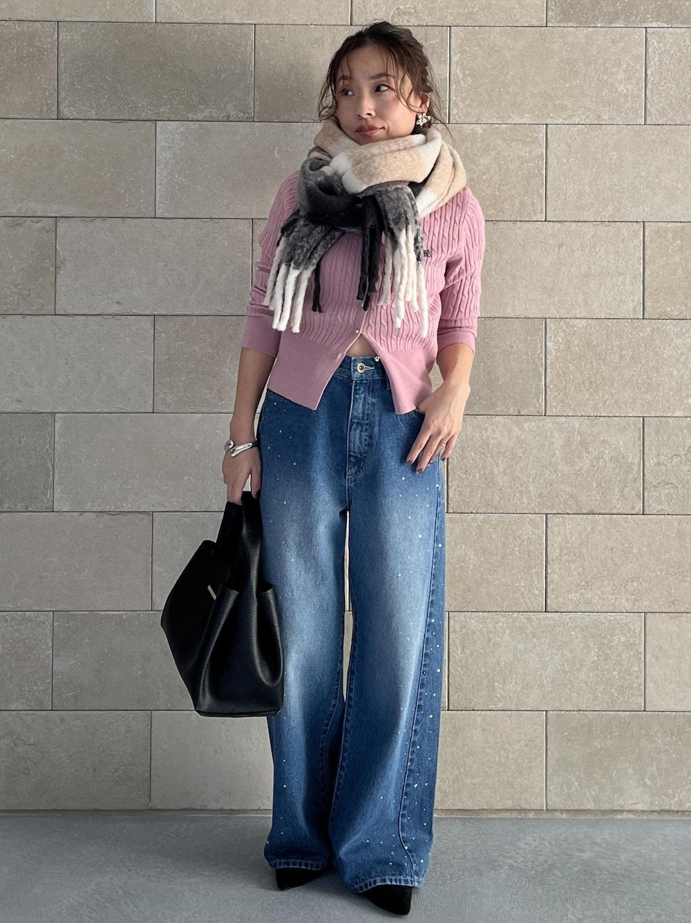 ブラック系のハンドバッグ、ピンク系のカーディガン/ボレロ、ブルー系のデニムパンツを着用したレディースの秋コーディネートの1枚目の写真